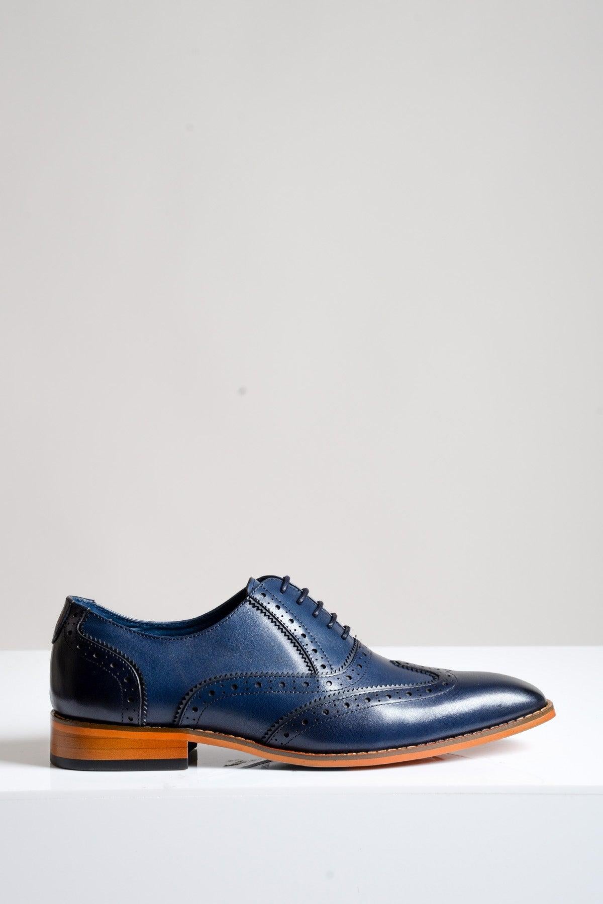 The MARCO Navy Blue Leather Oxford Wingtip Shoe by Marc Darcy, featuring hand-stitched full grain leather, brogue detailing, tan sole, and dark laces, is displayed on a white surface with a plain light gray background.