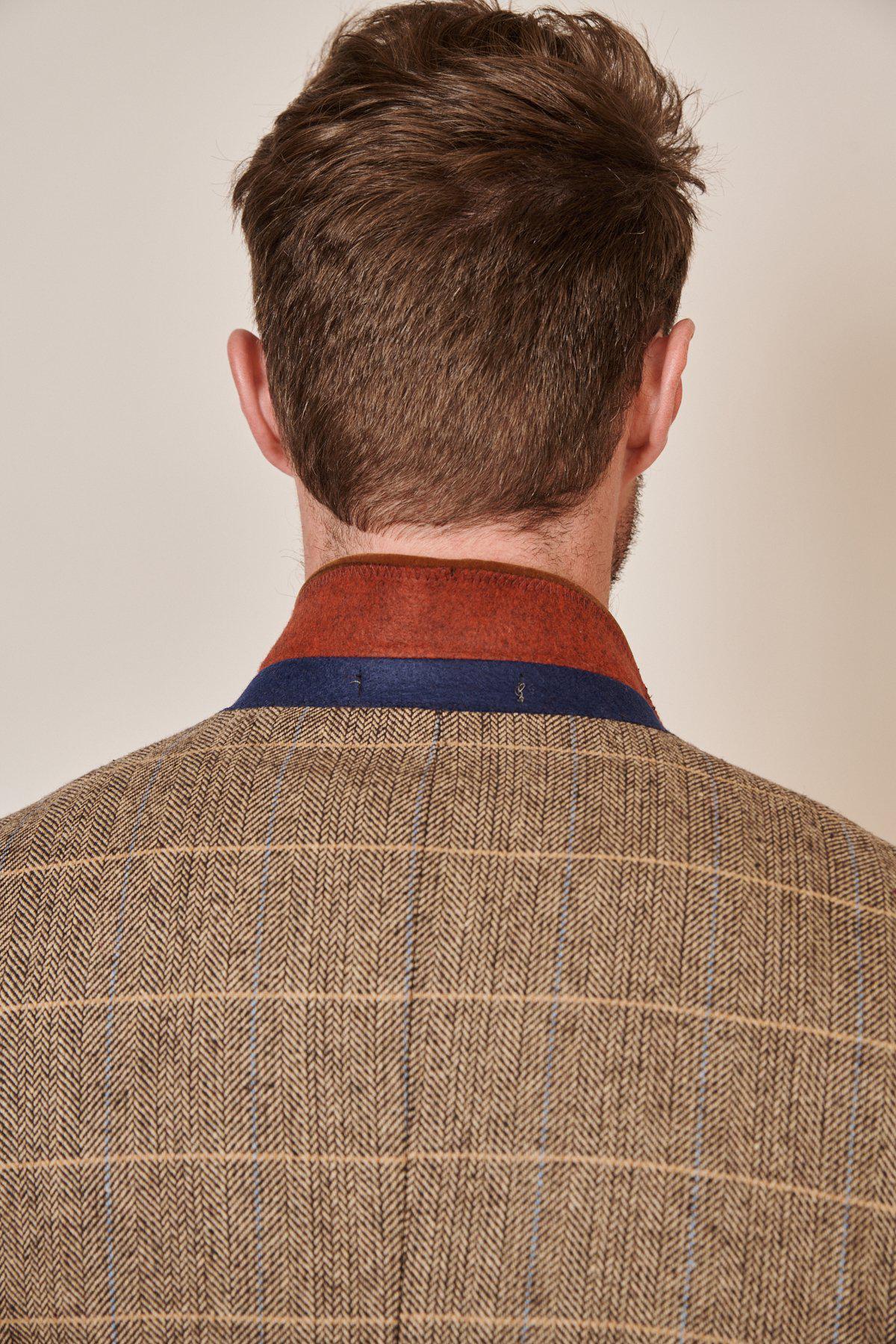 Rear view of a man wearing the marcdarcy WHU Collection TED Tan Tweed Suit with Dion Waistcoat, as worn by Lukasz Fabianski. Brown tweed features blue and tan plaid with a layered rust and navy collar.
