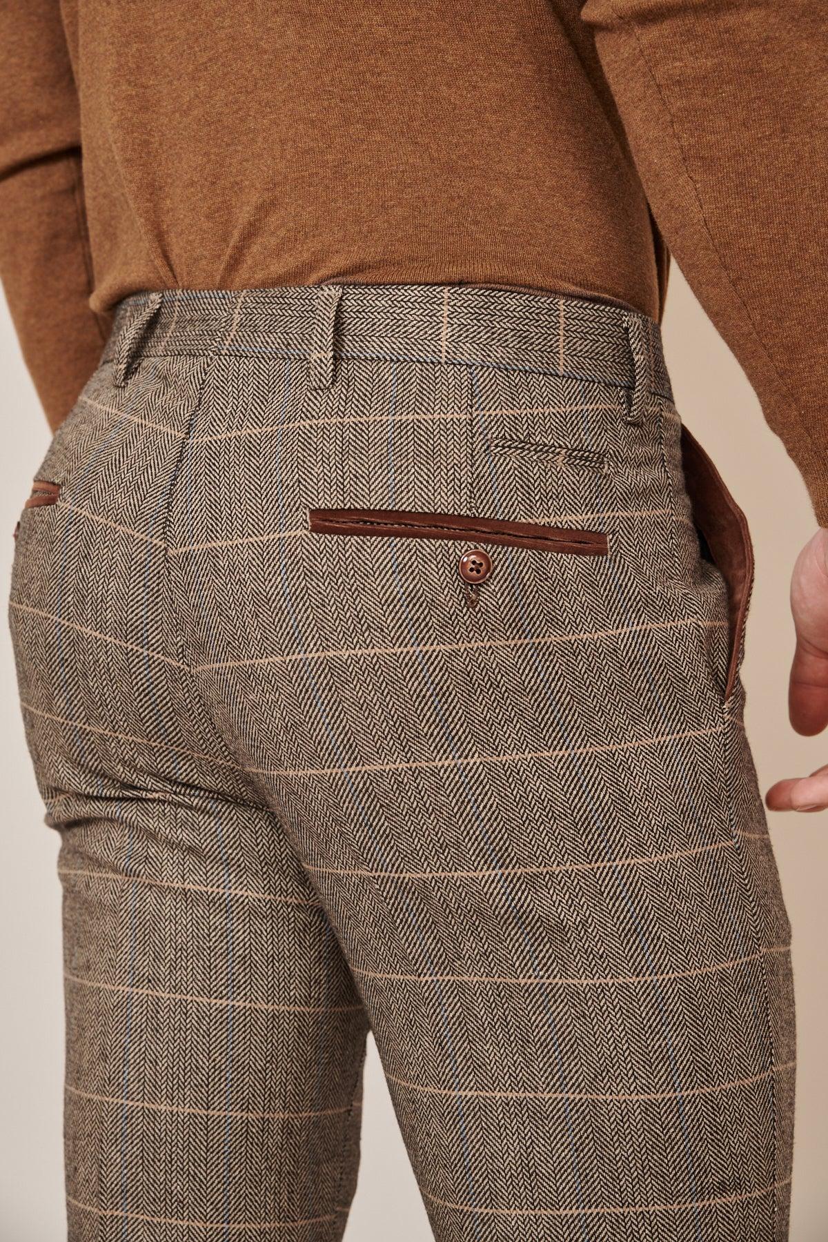 A person wearing the marcdarcy DX7 Tan Tweed Check Two Piece Suit, shown from the waist down and viewed from behind, featuring brown plaid dress pants with buttoned back pockets and a coordinating brown shirt with a velvet trim collar.