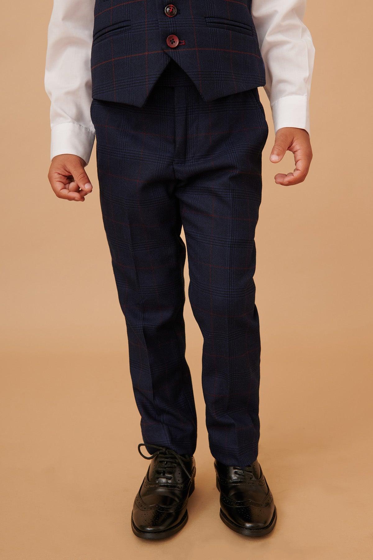 A boy wears the Marc Darcy EDINSON Children's Navy Wine Check Print Three Piece Suit with a white shirt and black shoes, standing against a beige background.