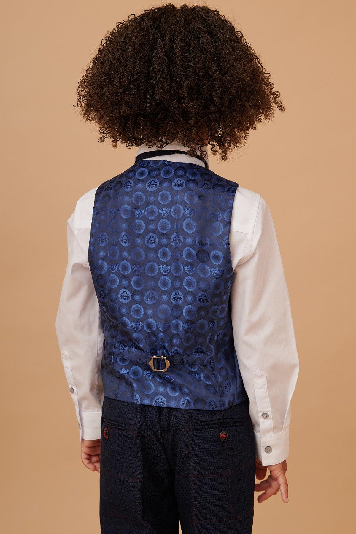 A child is seen from behind in the EDINSON - Childrens Navy Wine Check Print Three Piece Suit by Marc Darcy, with a white shirt and elegant vest, featuring dark trousers—perfect for matching an adult’s suit.