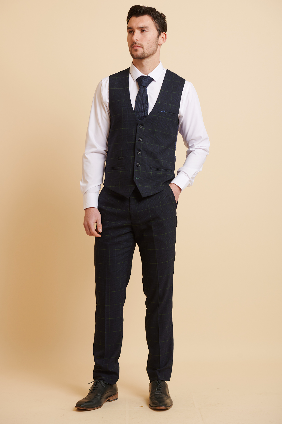 A man wears the Marc Darcy EDINSON Navy Green Check Single Breasted Waistcoat with matching pants, a white shirt, and a navy tie.