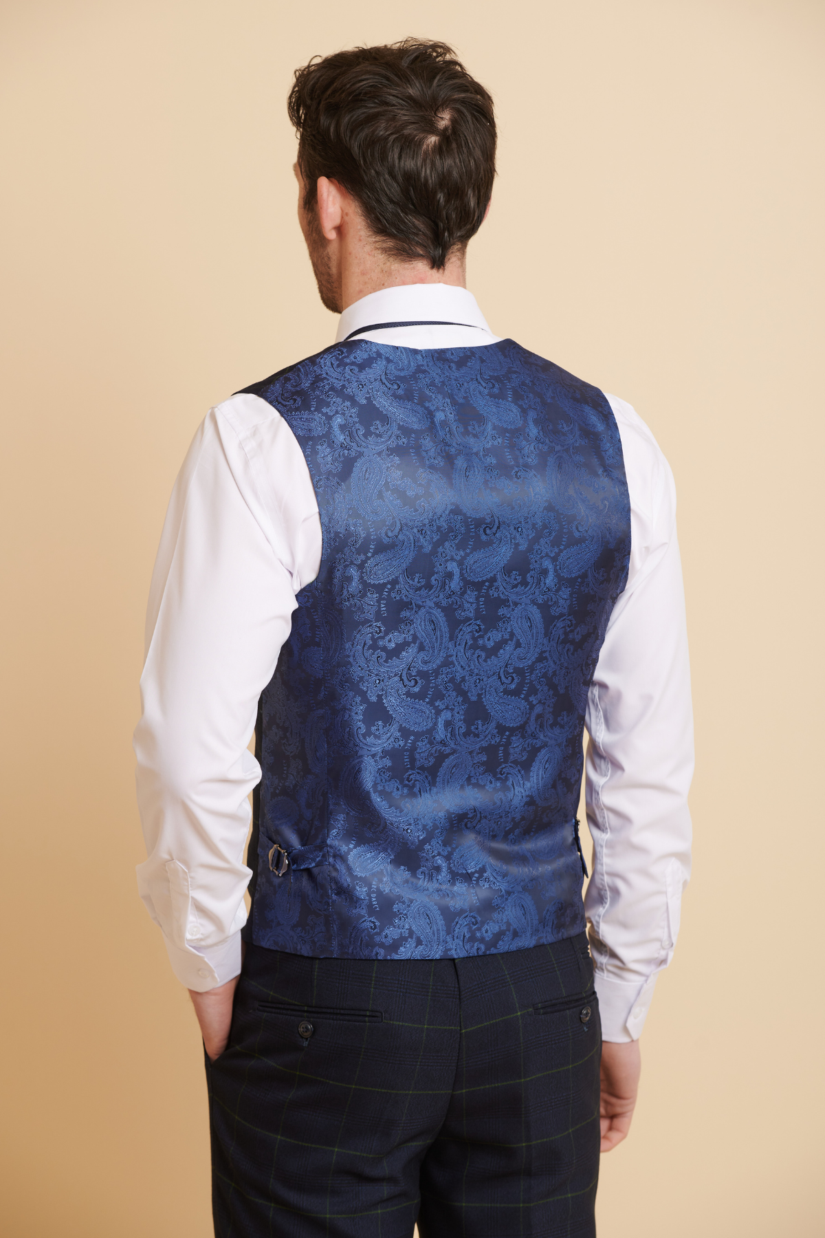 Back view of a man in a slim-fit navy paisley jacquard waistcoat and white shirt, paired with navy green check trousers from Marc Darcy’s The Everton Collection | James Tarkowski in EDINSON—ideal for refining your three-piece look.