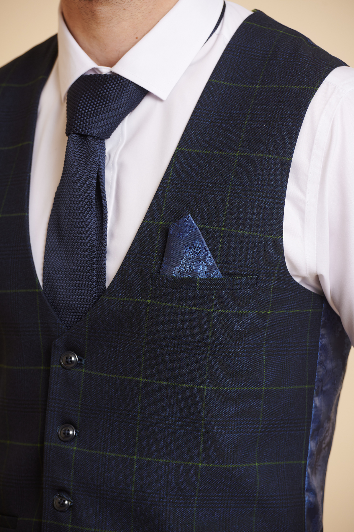 A man wears a white shirt, dark blue textured tie, and a Marc Darcy EDINSON navy green check single breasted waistcoat in slim fit with a matching blue pocket square. His face is not shown.