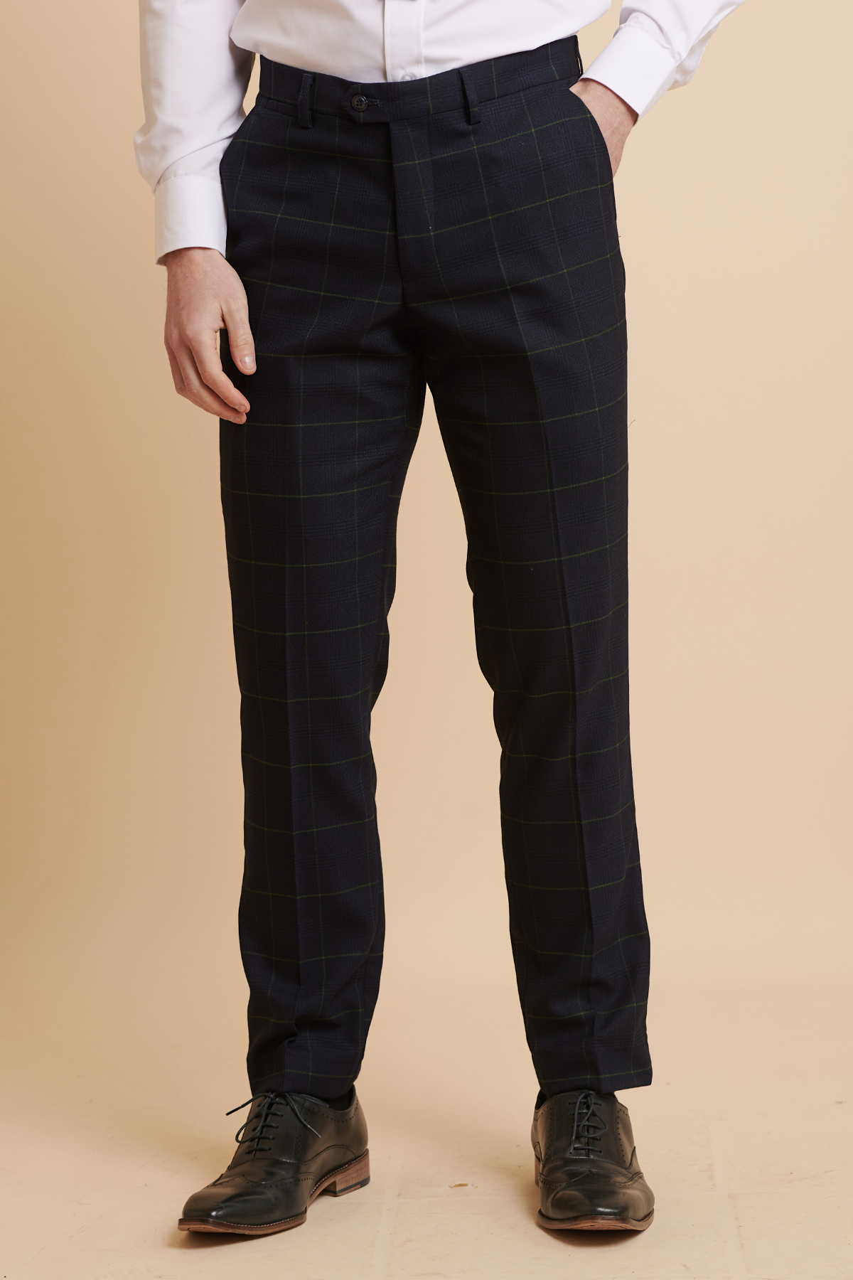 A person models Marc Darcy's EDINSON Navy Green Check Trousers with a white shirt and black leather dress shoes against a beige background, with their head out of frame.