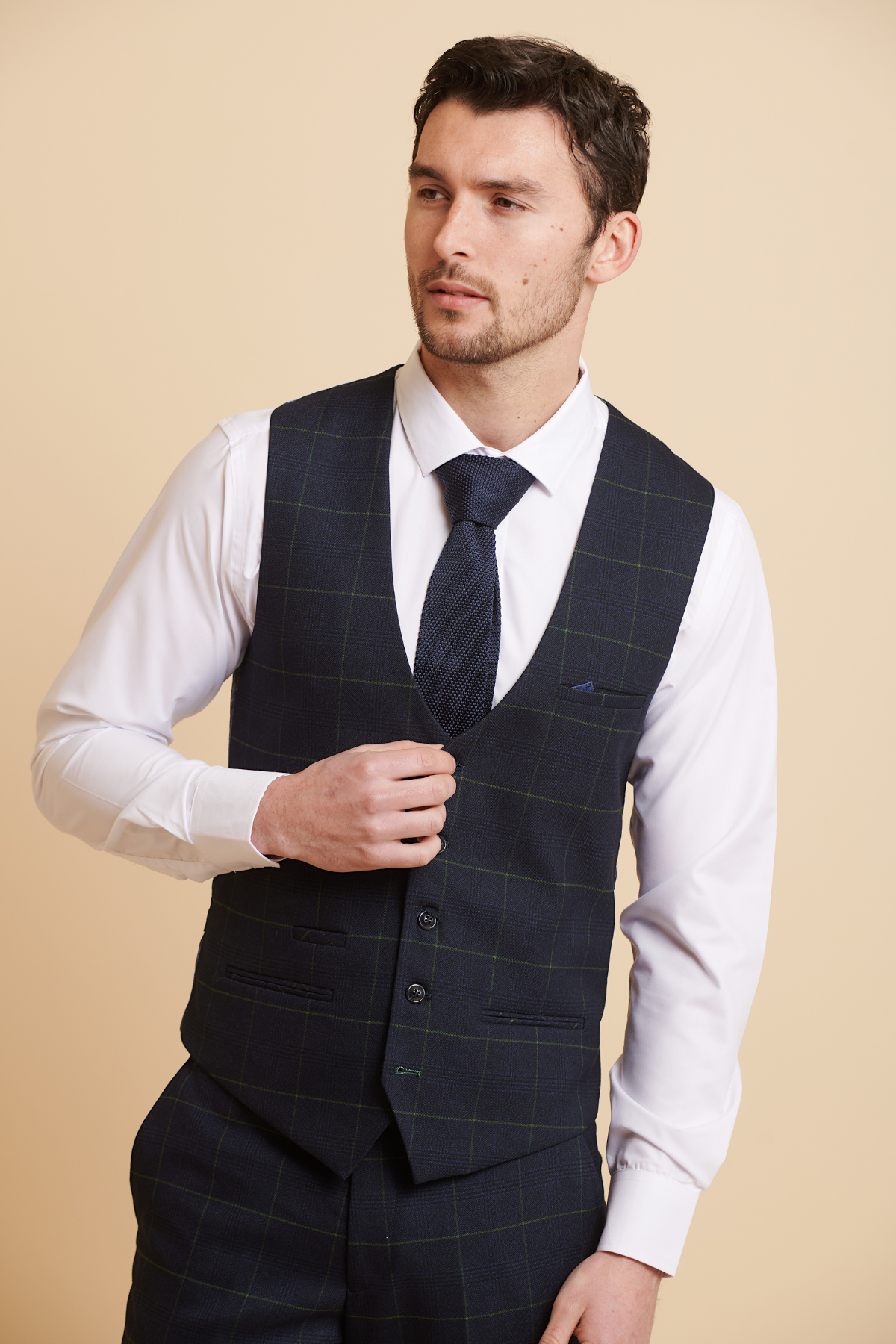 Man wearing a slim fit Marc Darcy EDINSON navy green check single breasted waistcoat over a white dress shirt, paired with a navy knit tie and pocket square.