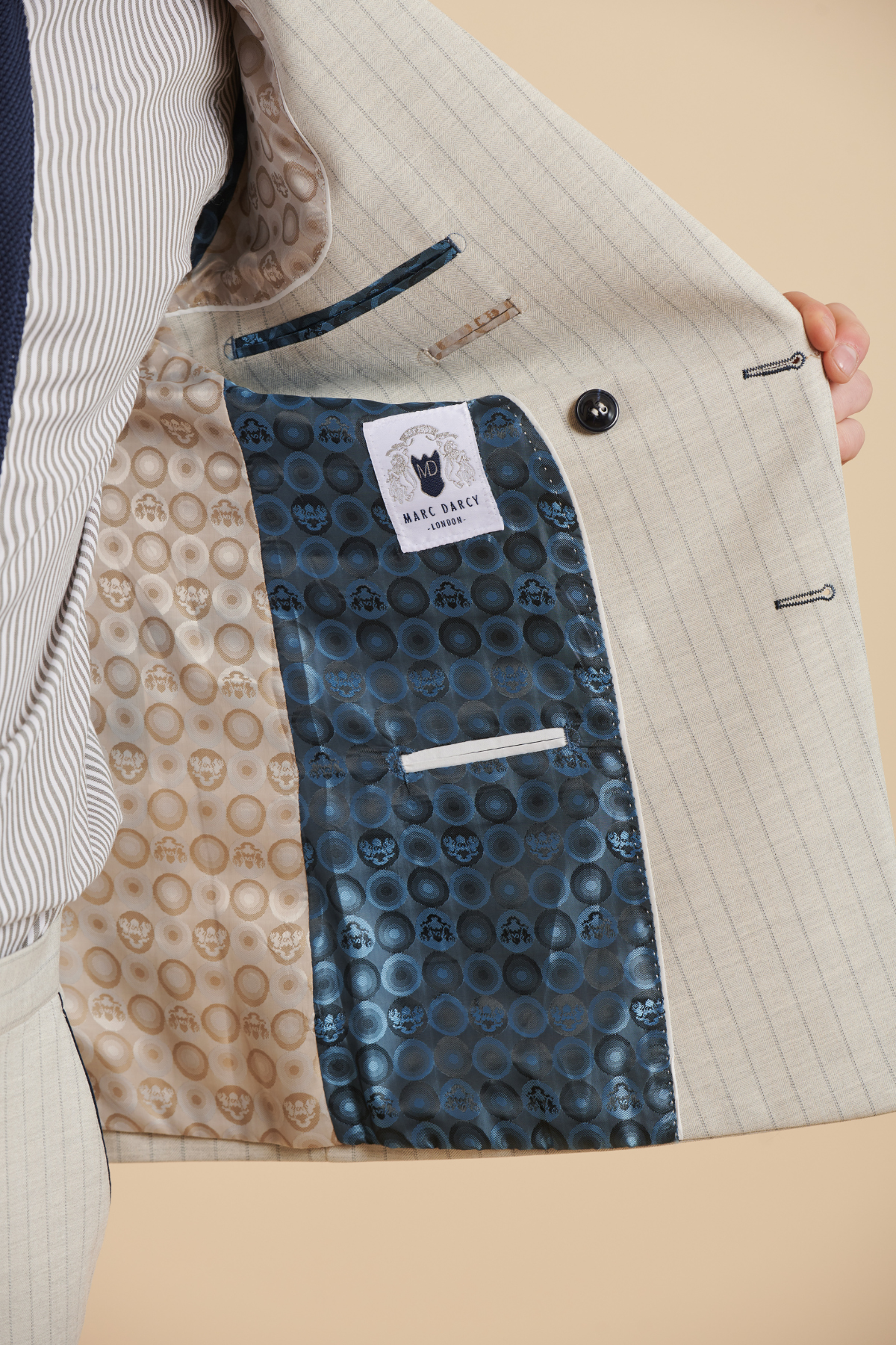 The interior of Marc Darcy's The Everton Collection | Beto In GRANT Stone Pinstripe Double Breasted Suit features a blue and gold circular patterned lining, inner pocket, and branded label—ideal for any three piece or slim fit suit ensemble.
