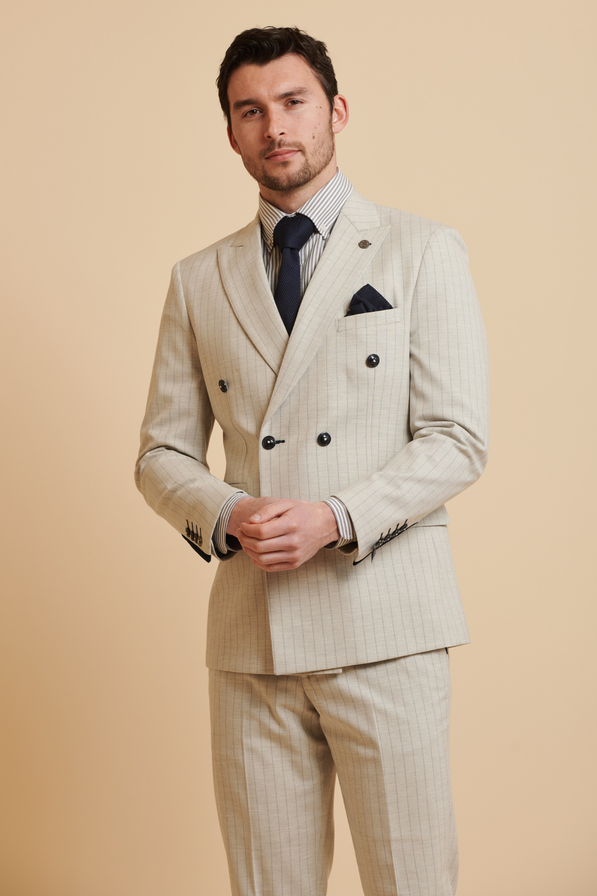 Man wearing the Marc Darcy Everton Collection's Beto in Grant Stone Pinstripe Double Breasted Suit, styled with a dark tie, striped shirt, and pocket square.