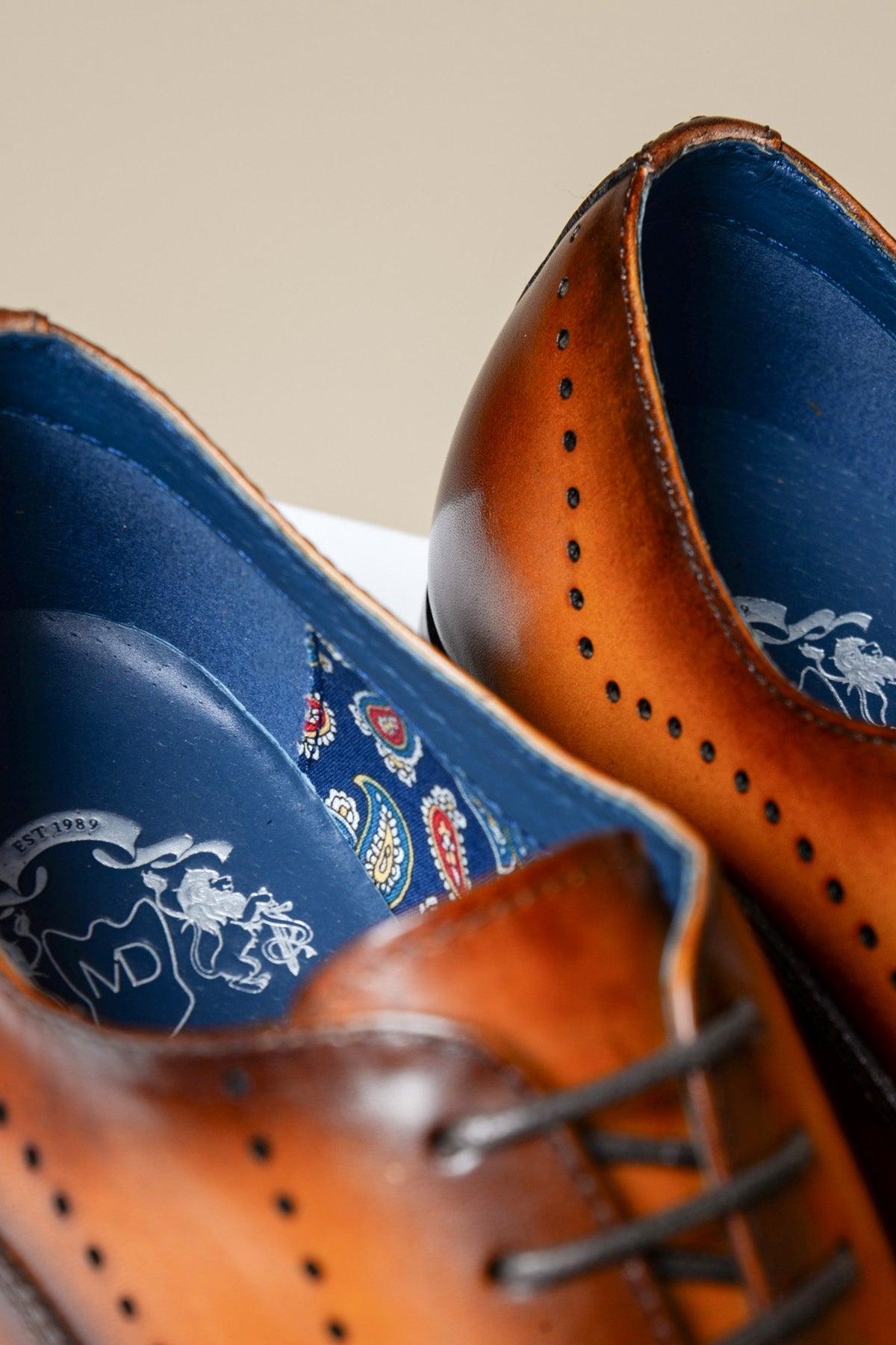 Close-up of Marc Darcy’s JAKE Tan Leather Contrast Oxford Shoes: ideal for business or formal wear, featuring brown laces, decorative perforations, and a blue paisley-patterned insole with logo.