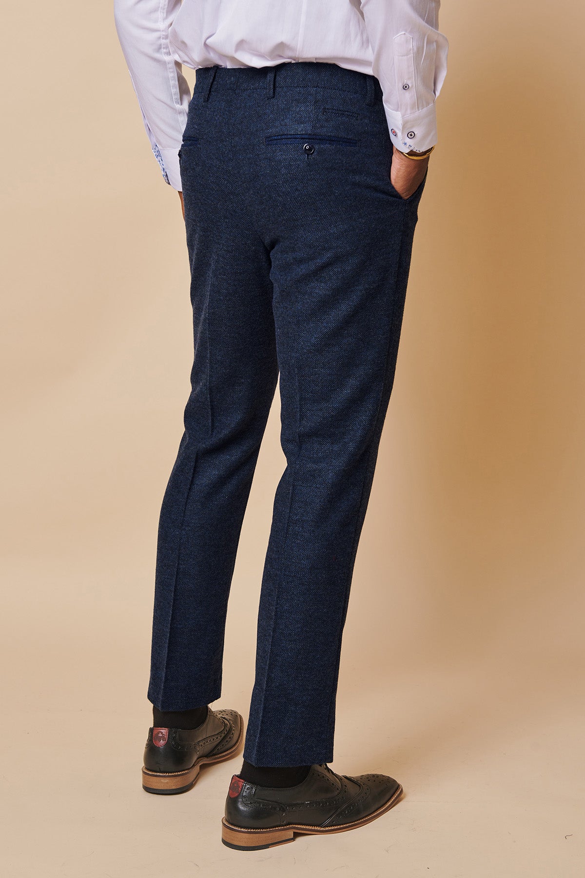 Close-up of a man wearing marcdarcy MARLOW - Navy Tweed Trousers, styled with a white shirt and black brogue shoes against a beige background.