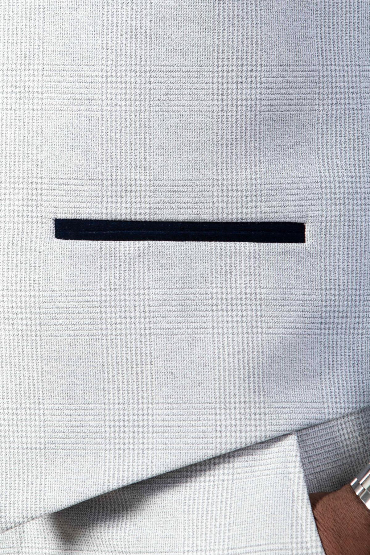 Close-up of Marc Darcy's "The WBA Collection - BROMLEY Stone Suit" jacket, featuring a light grey Prince of Wales check and a black welt pocket.