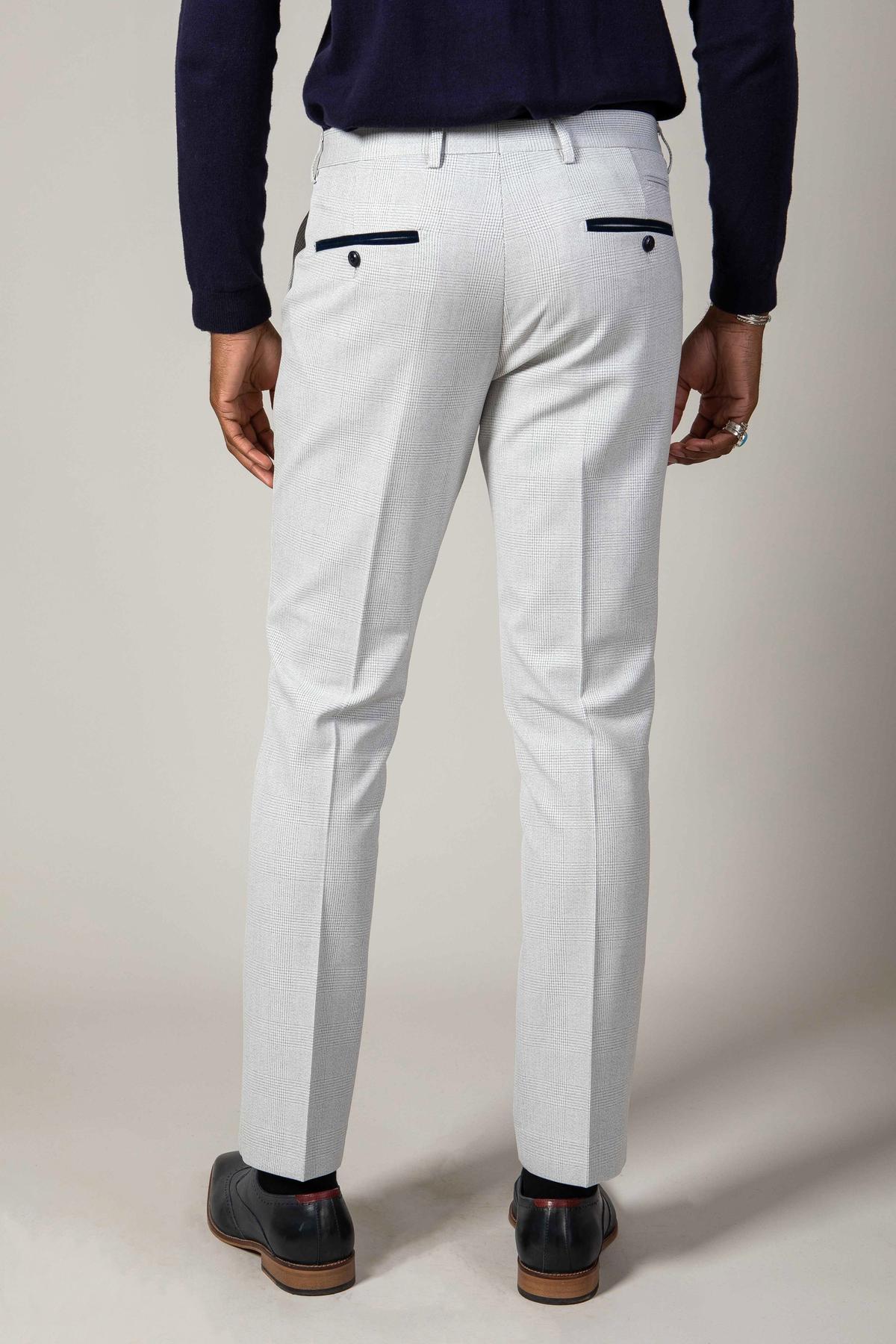 A person wearing the Marc Darcy WBA Collection - BROMLEY Stone Suit tailored pants, paired with a dark long-sleeve top and black dress shoes, shown from the back against a plain background.