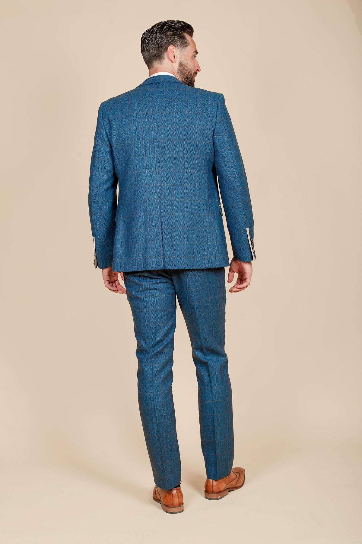 A man is seen from behind wearing the marcdarcy Everton Collection Jarrad Branthwaite in DION Blue Tweed Check Suit, paired with brown leather shoes.