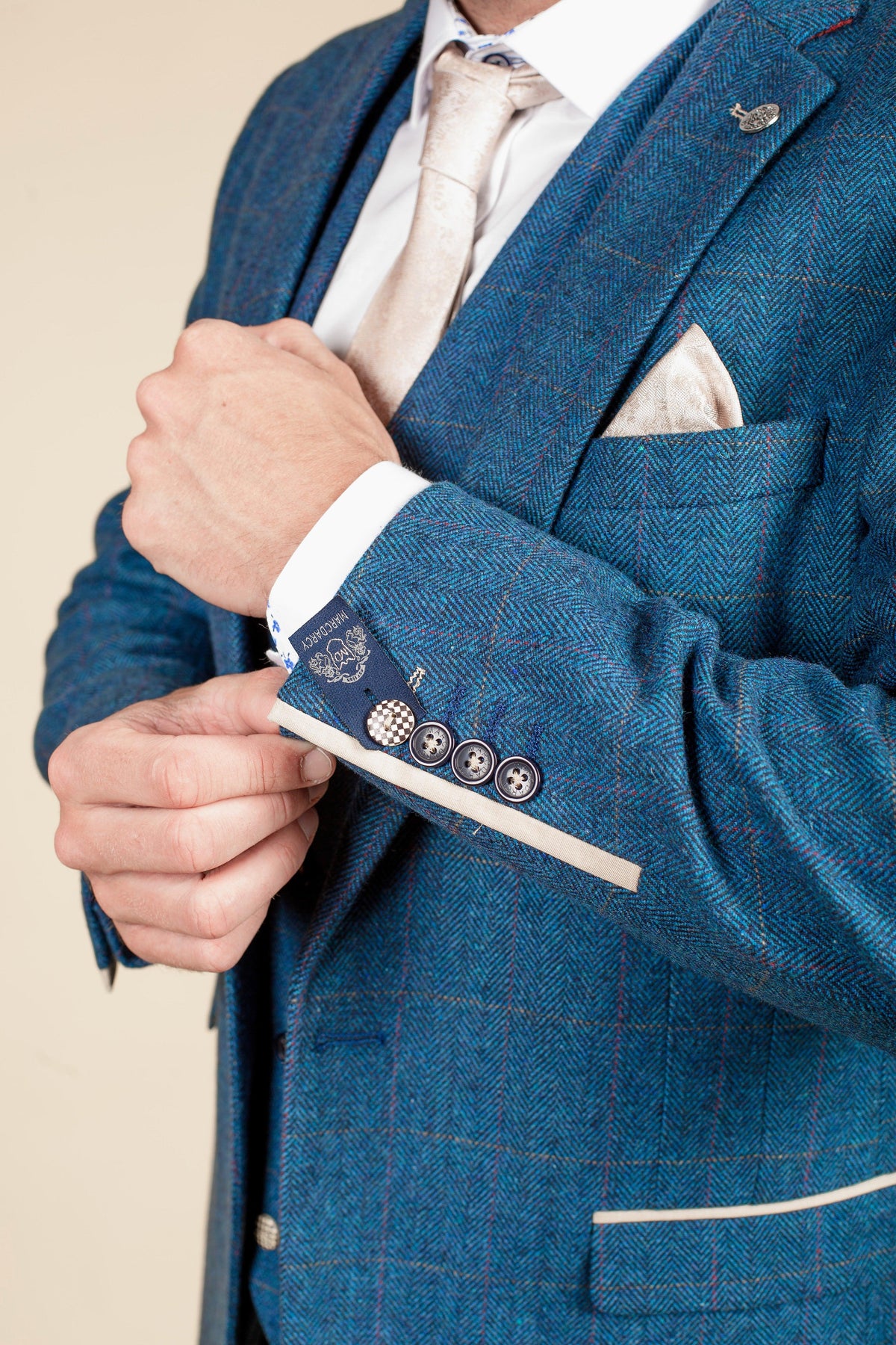 Ashley Young wears the marcdarcy Everton Collection DION Blue Tweed Check Suit, featuring detailed stitching and buttons, paired with a white shirt, beige tie, and matching pocket square.