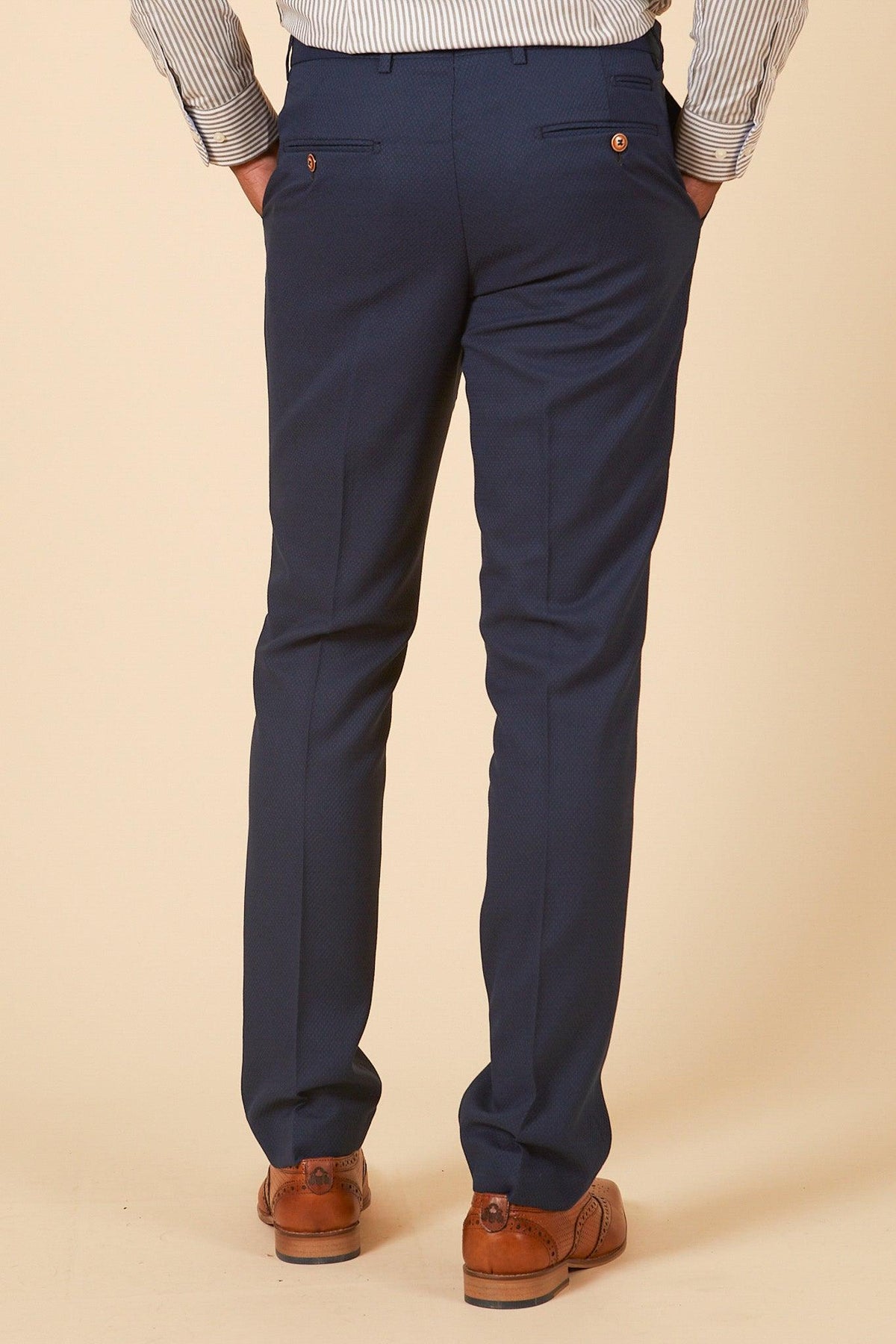 A person wearing the marcdarcy Official Leicester City F.C. Club Suit—MAX Royal Blue Suit with Kelvin Tan Waistcoat—is shown from the back with hands in pockets, set against a plain light beige background.