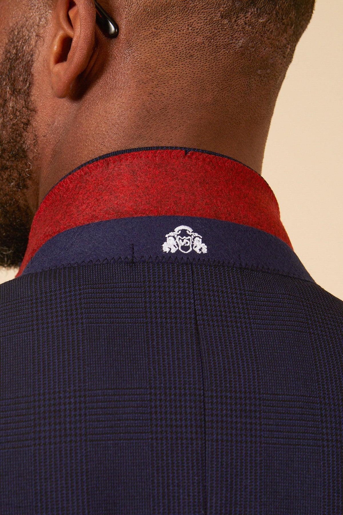 Close-up of the back of West Ham United footballer Jarrod Bowen in a Marc Darcy Bromley navy check three-piece suit, featuring a subtle Prince of Wales pattern and a red inner collar with a white embroidered emblem.