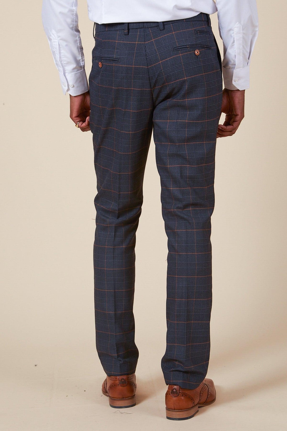 A man wears marcdarcy’s WBA Collection JENSON Marine Navy Check Suit, as worn by John Swift, paired with brown wingtip shoes.