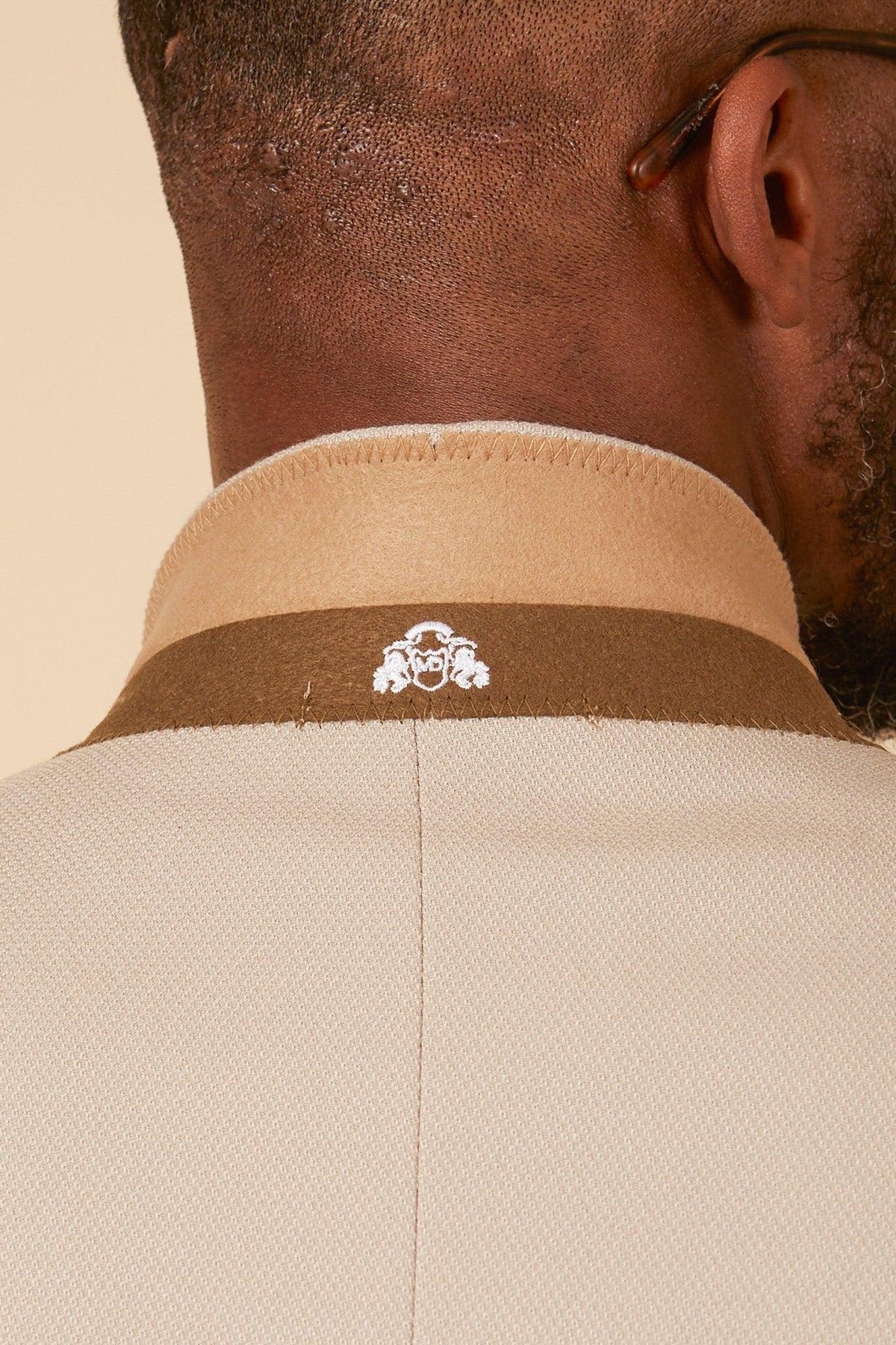 Close-up of a mans neck and head, with glasses, showcasing the collar of the Marc Darcy Leicester City F.C. Collection - HM5 Stone Suit with Kelvin Black Waistcoat as worn by Mads Hermansen.