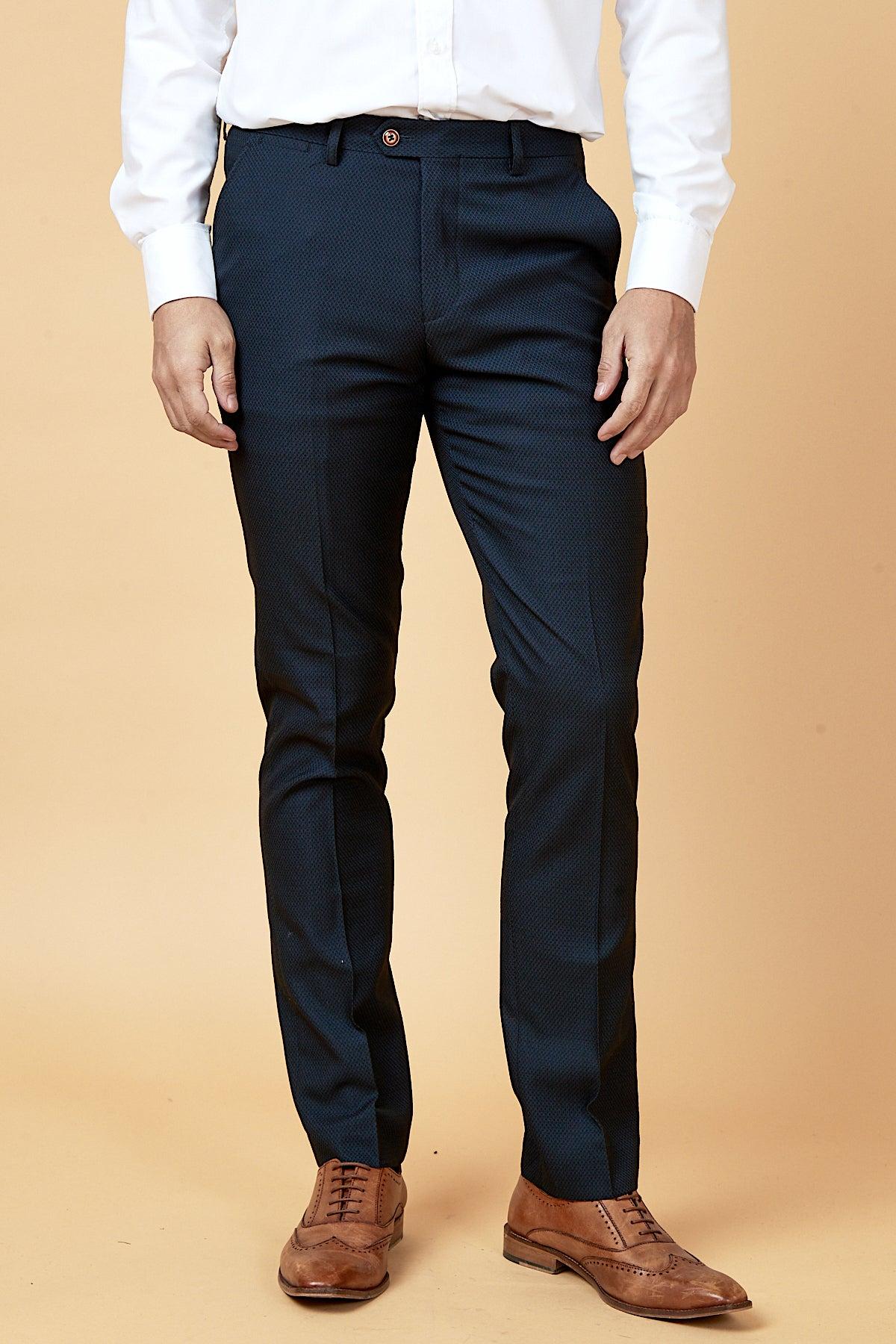 A man wears a crisp white dress shirt, The WHU Collection - MAX Navy Three Piece Suit by marcdarcy as worn by Max Kilman, and brown wingtip dress shoes.
