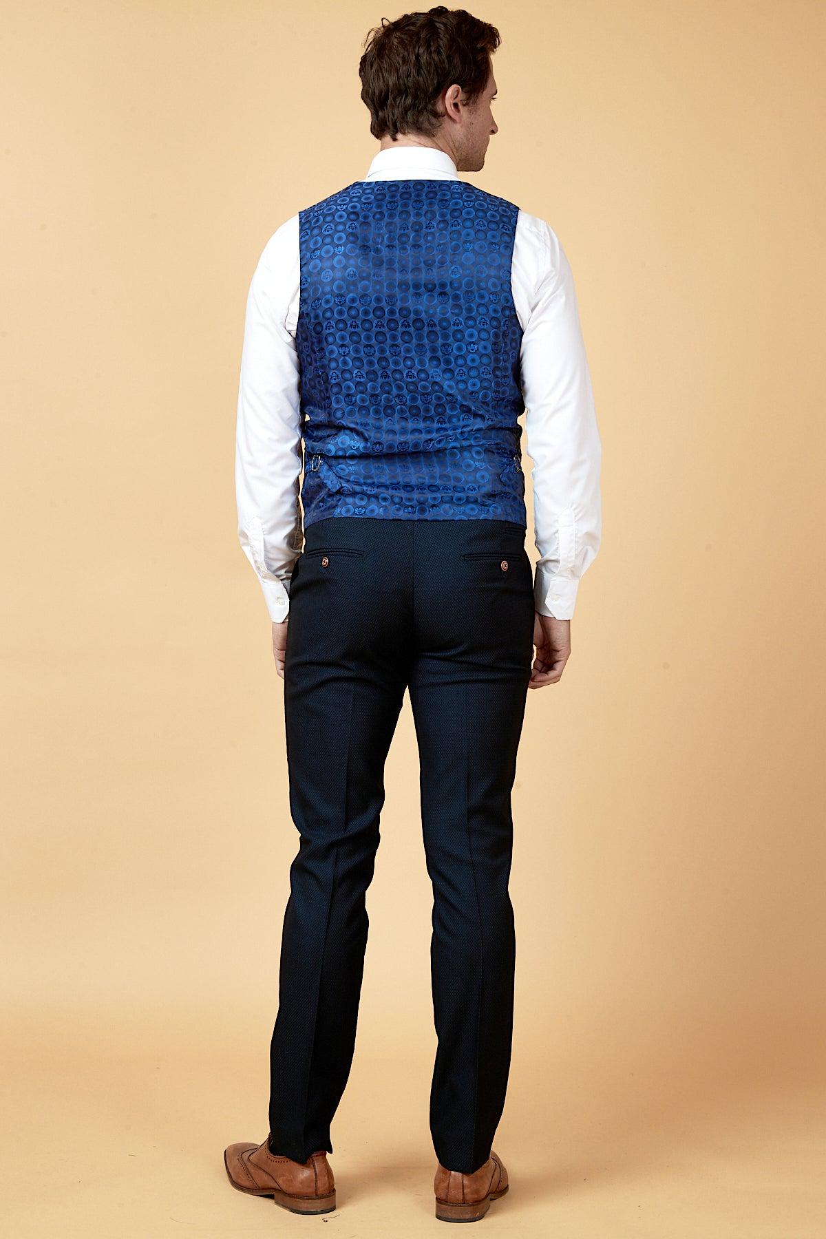 Man in the marcdarcy WHU Collection MAX Navy Three Piece Suit, as worn by Max Kilman, paired with a white shirt and brown shoes, is seen from behind—offering a modern take on the classic men's suit.