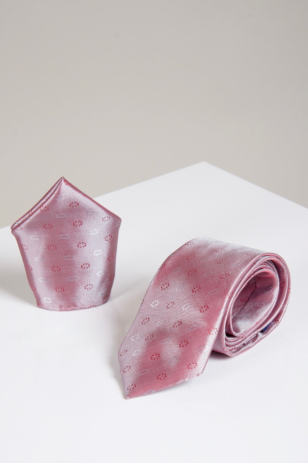 The TS CIRCLE - Pink Circle Tie and Pocket Square Set by Accessory is displayed on a white surface with a light gray background, making it a stylish addition to your men’s accessories collection.