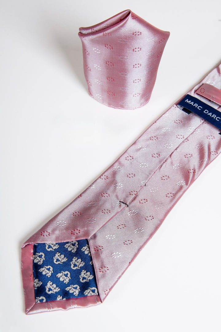 The TS CIRCLE - Pink Circle Tie and Pocket Square Set by Accessory is shown on a white surface, with the tie’s tip lined in blue floral fabric and a Marc Darcy label on the back—ideal for elevating your tuxedo look.