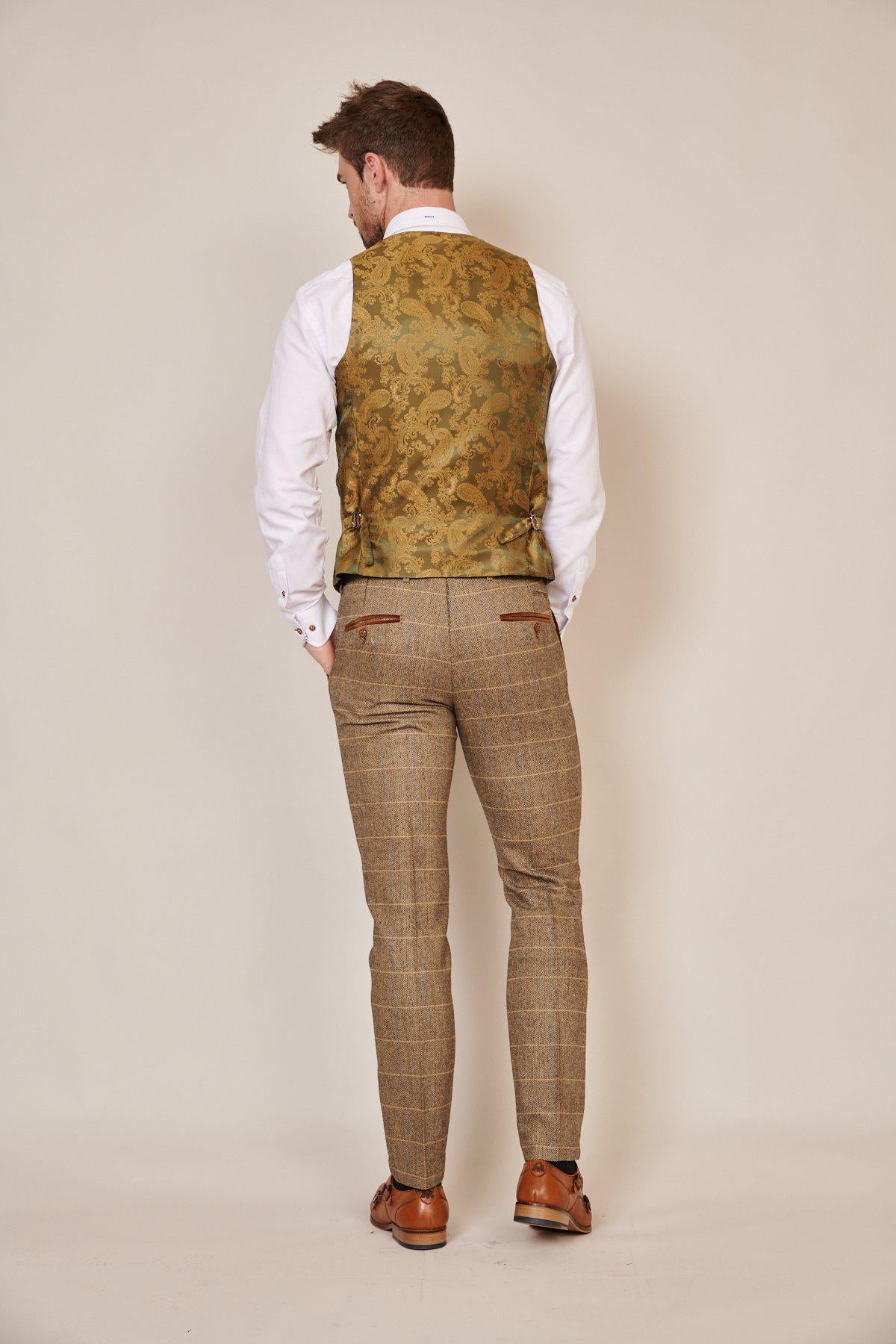 A man, facing away from the camera, wears marcdarcy's WHU Collection - TED Tan Tweed Check Three Piece Suit as worn by Lukasz Fabianski, set against a plain beige background.