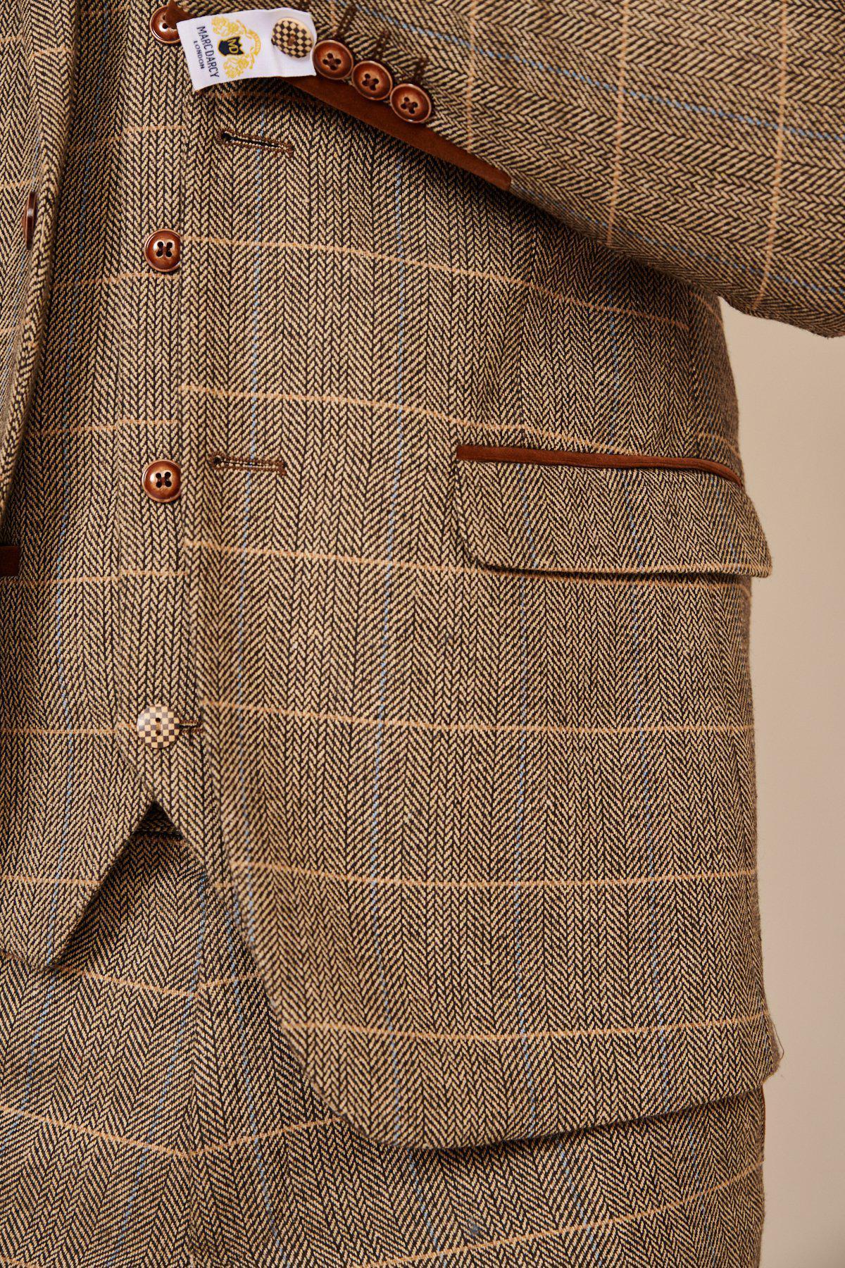 Close-up of marcdarcy’s WHU Collection - TED Tan Tweed Suit with Dion Waistcoat, as worn by Lukasz Fabianski, showcasing English gent style with herringbone pattern, button details, pocket flap, and branding tag near the cuff.