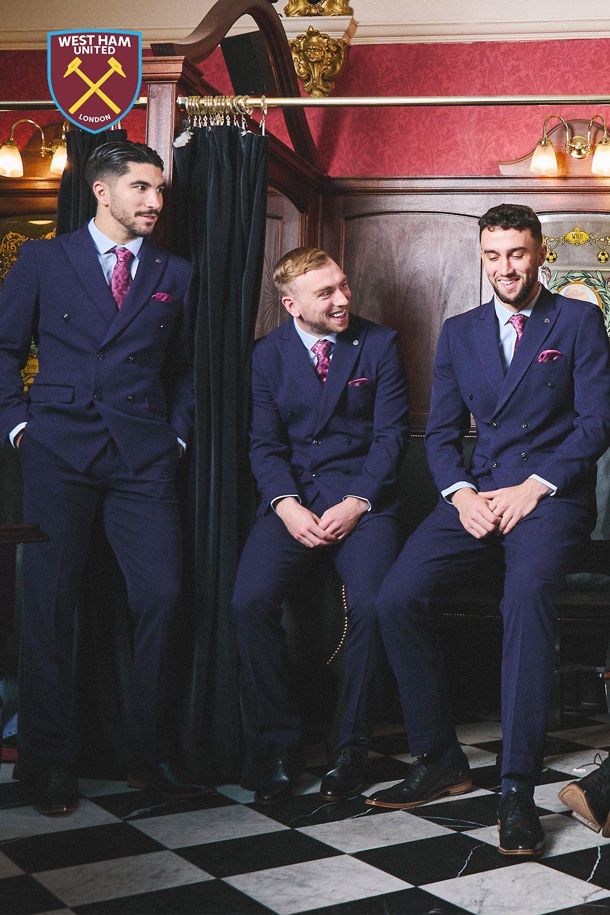 Three men wear matching BROMLEY Navy Double Breasted Suits by Marc Darcy, the Official West Ham United Club Suit, paired with pink ties and pocket squares in a vintage room. The West Ham United crest appears in the top left corner.