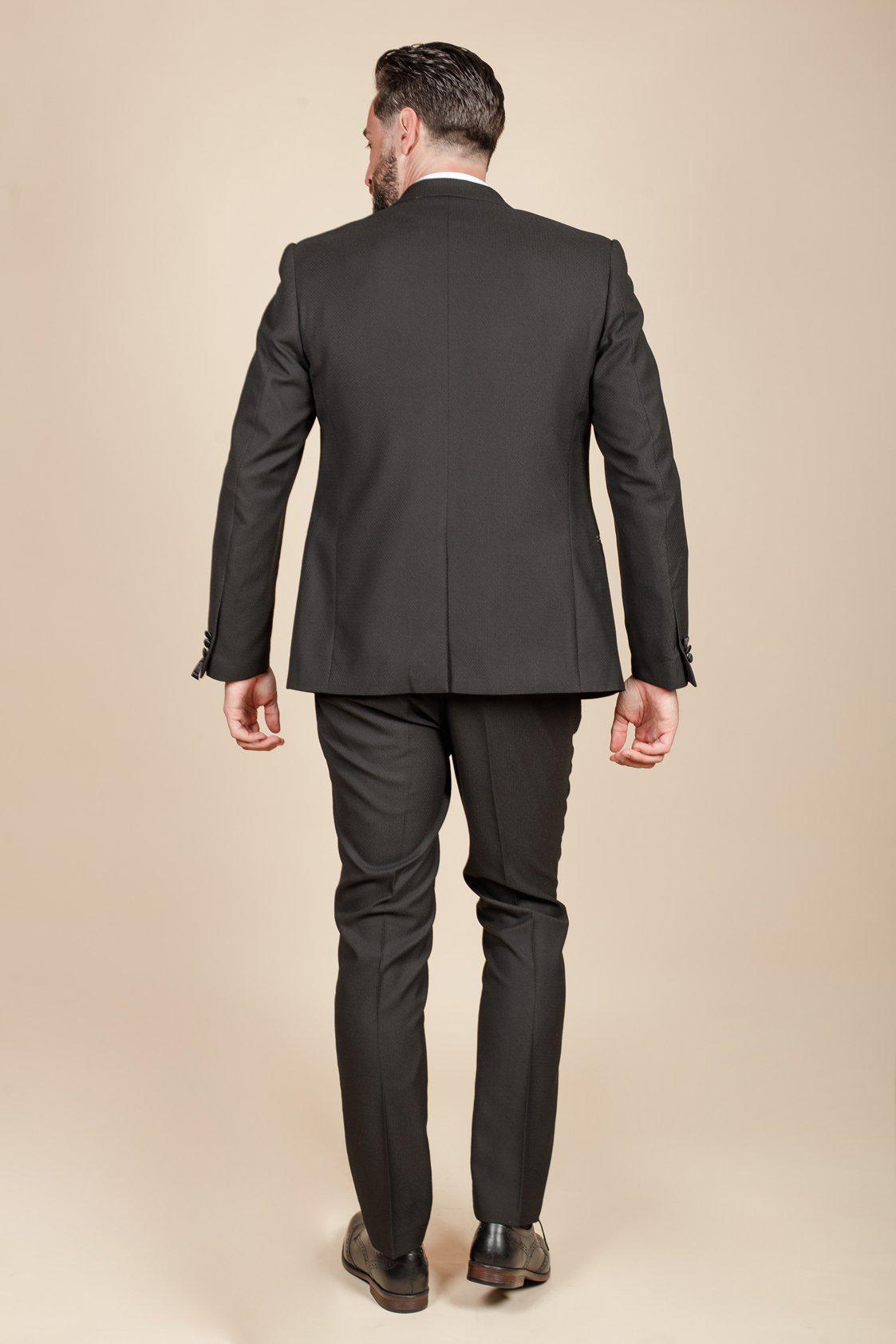 Dylan Wilson (Liam McCheyne) wears the marcdarcy Dalton Black Tuxedo Suit, standing with his back to the camera against a beige backdrop—sleek style and dress shoes ideal for black tie events.