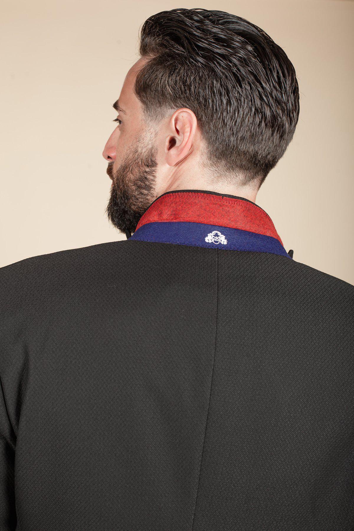 Liam McCheyne as Coronation Street’s Dylan Wilson is seen from behind in the marcdarcy Dalton Black Tuxedo Suit, featuring a slim fit design, red and blue collar accents, and a small white embroidered detail at the collar’s center.