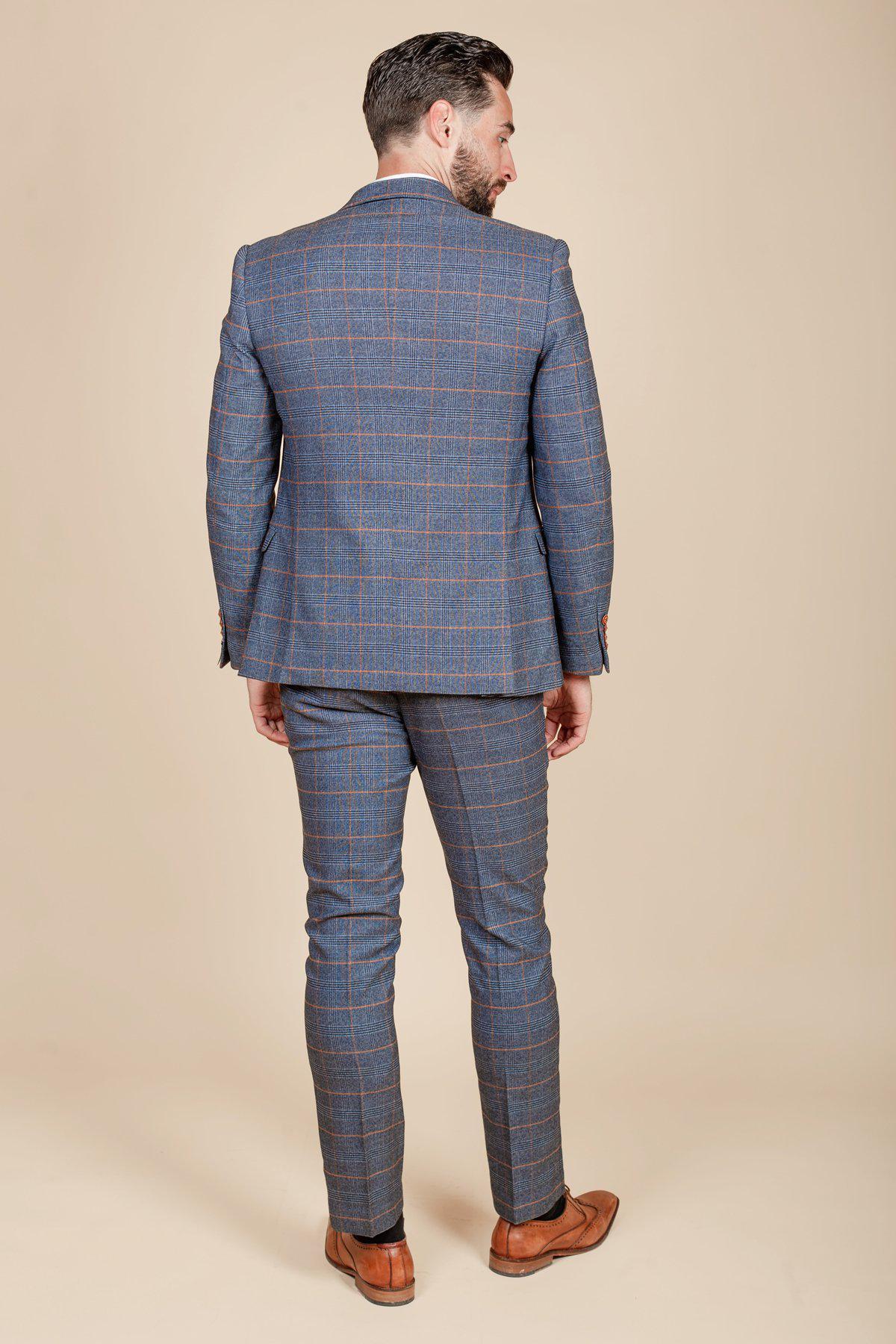 Daniel Osbourne (Rob Mallard) from Coronation Street wears the marcdarcy JENSON Sky Blue Check Suit with matching trousers and tan shoes, standing against a beige background.