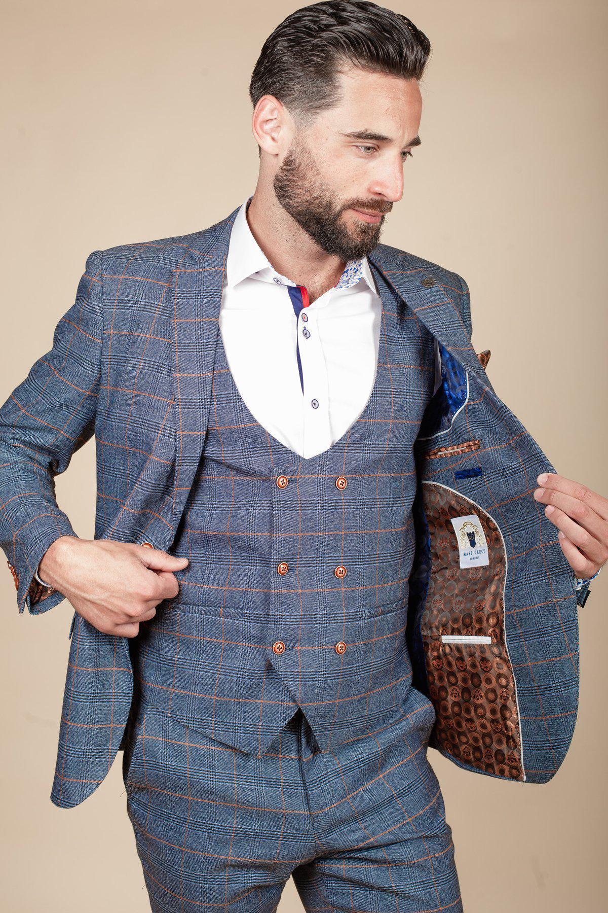 Daniel Osbourne (Rob Mallard) wears the marcdarcy JENSON Sky Blue Check Suit—a slim fit three-piece with double-breasted vest and white shirt—showing its brown patterned lining while looking slightly left.