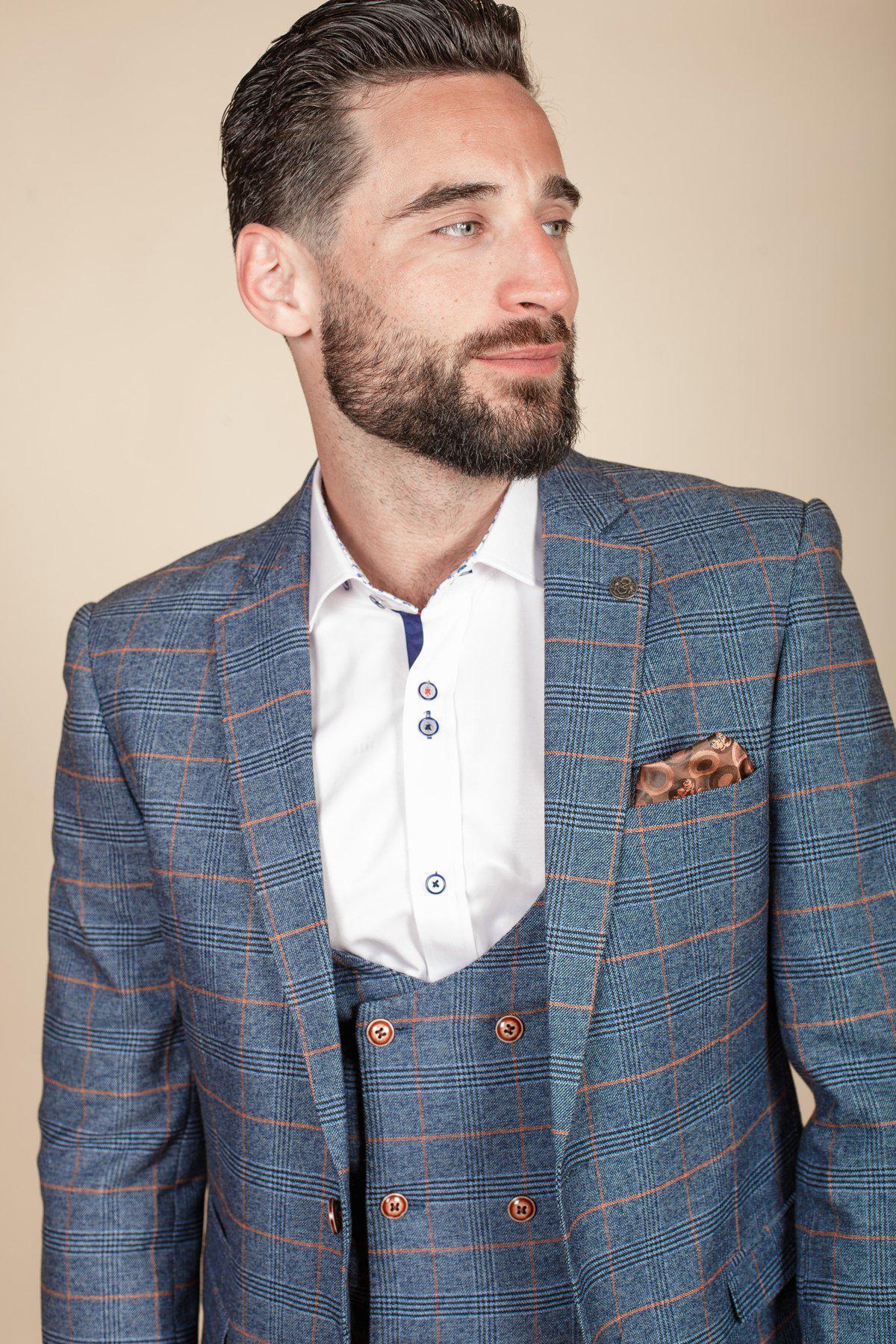 Daniel Osbourne (Rob Mallard) from Coronation Street wears a marcdarcy JENSON sky blue check suit with orange and white pattern, paired with a white shirt and tan pocket square, looking to the right.