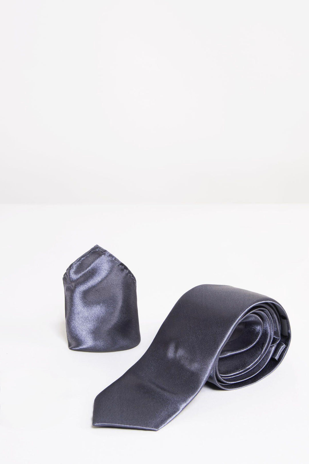 The Accessory ST - Satin Tie and Pocket Square Set in Charcoal features a sleek, rolled dark gray tie beside a matching pocket square, beautifully arranged on a white surface with a plain background.