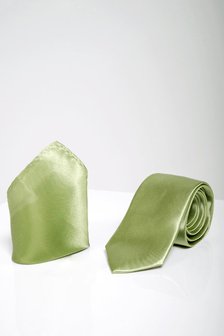 The ST - Satin Tie and Pocket Square Set In Green by Accessory features a light green satin tie and matching pocket square, elegantly rolled up on a white surface.