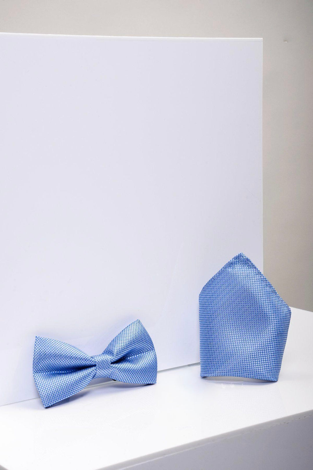 The Accessory TB17 Birdseye Print Bow Tie and Pocket Square Set in blue is shown on a white surface with a plain white background—an ideal wedding accessory.