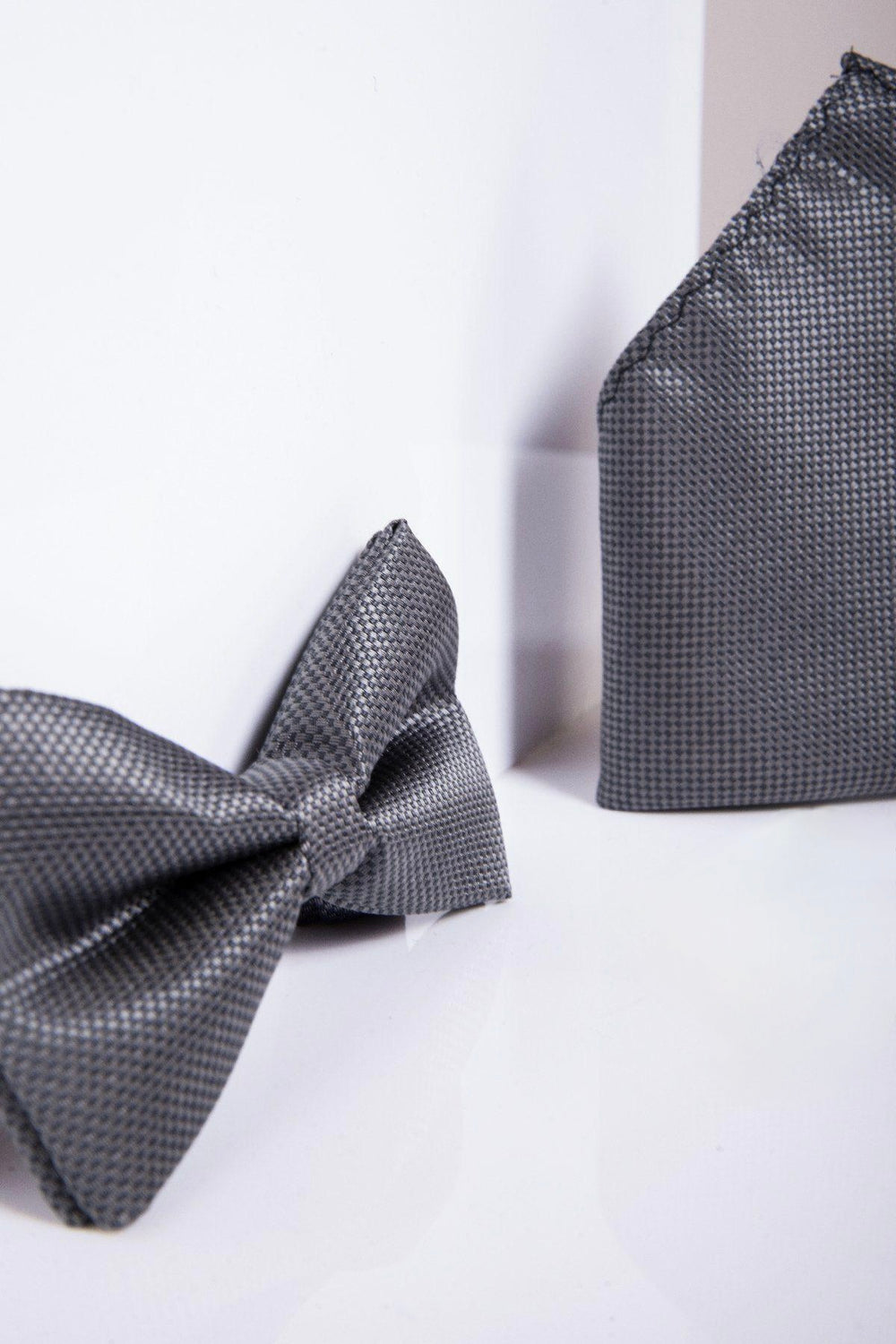A close-up of the TB17 - Birdseye Print Bow Tie and Pocket Square Set in Charcoal by Accessory, featuring a stylish pre-tied design and textured finish, displayed against a white background.