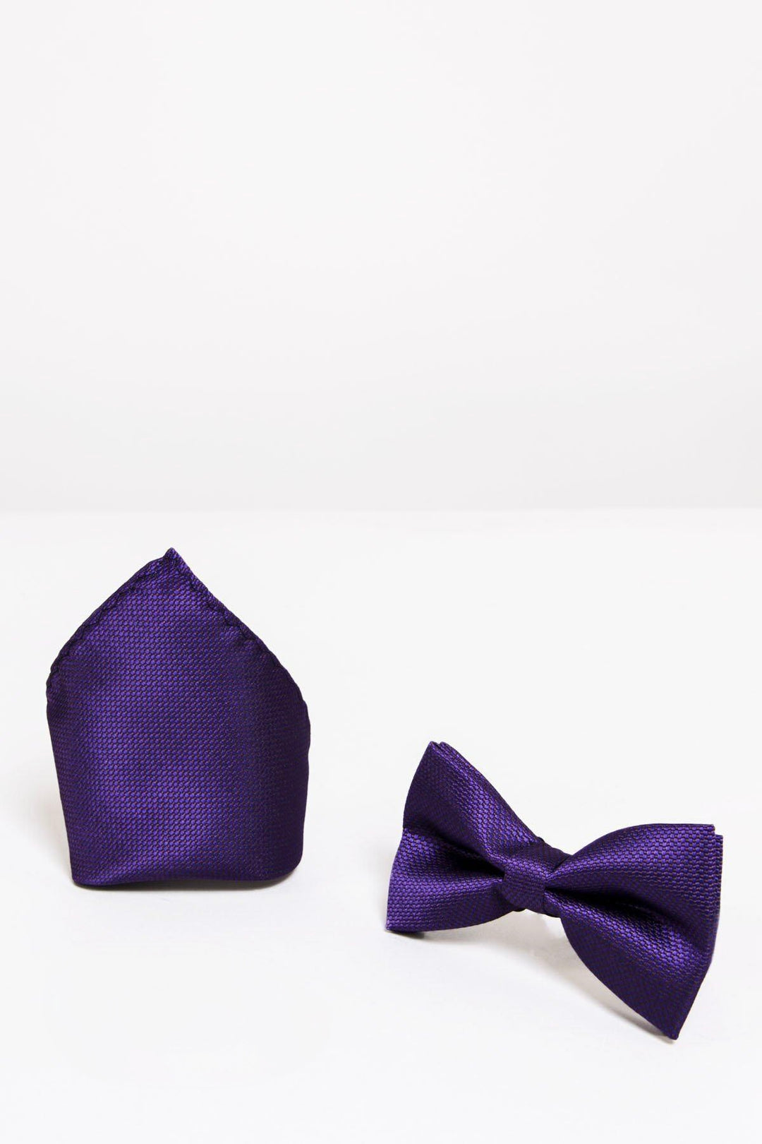 The Accessory TB17 Birdseye Print Bow Tie and Pocket Square Set in Purple features a textured, pre-tied bow tie and matching pocket square, both displayed neatly on a white surface against a plain white background.