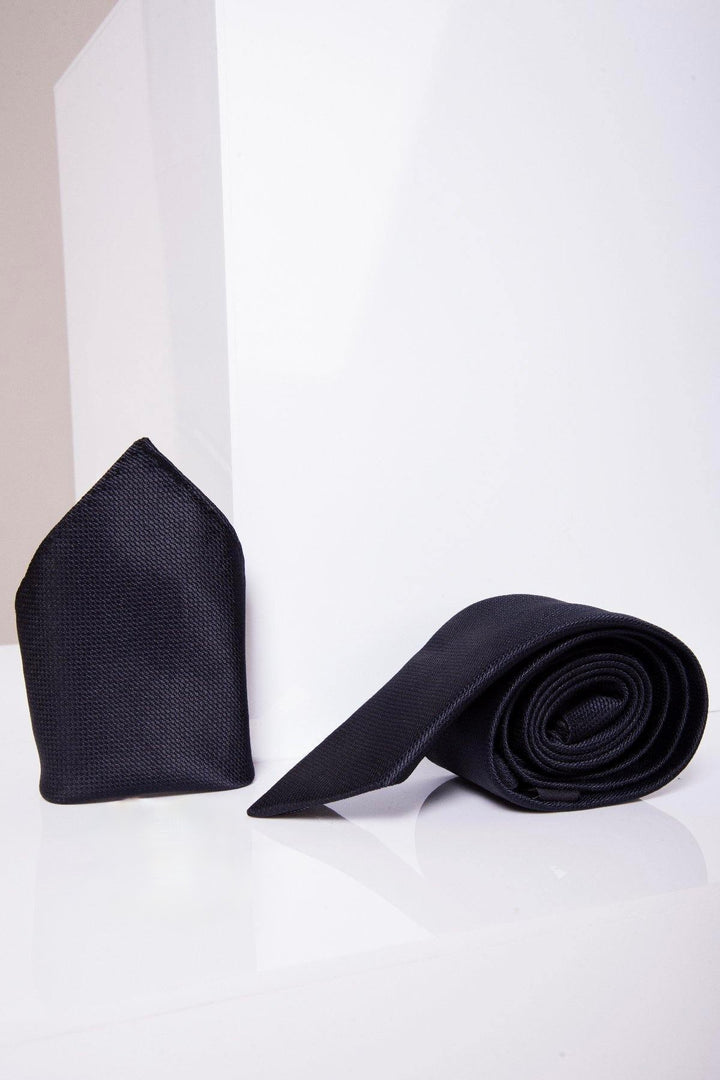 The Marc Darcy TB17 Birdseye Tie and Pocket Square Set in Midnight features a neatly rolled tie beside a matching pocket square on a glossy white surface—a refined wedding accessory against a crisp, geometric backdrop.