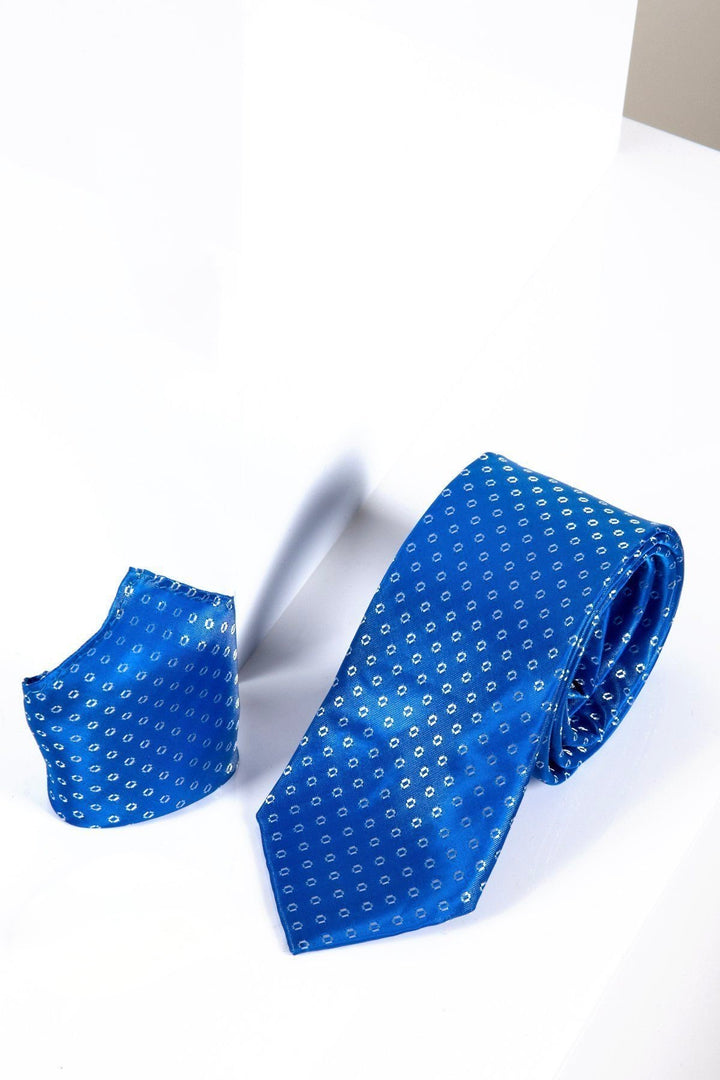 The Marc Darcy TS TUBES Blue Spot Tie and Pocket Square Set features a bright blue geometric dot pattern with luxury monogrammed lining, displayed against a white and beige background.