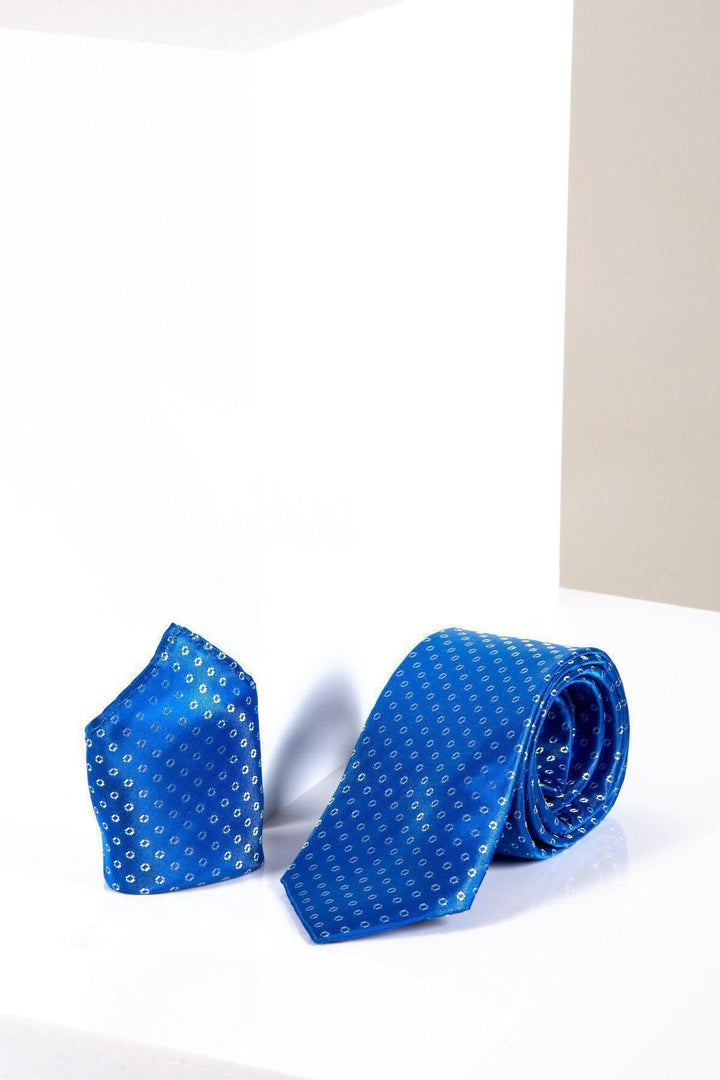 The TS TUBES - Blue Spot Tie and Pocket Square Set by Marc Darcy features small white dots, shown on a glossy white surface with a white and beige background—ideal for adding sophistication to formal outfits.