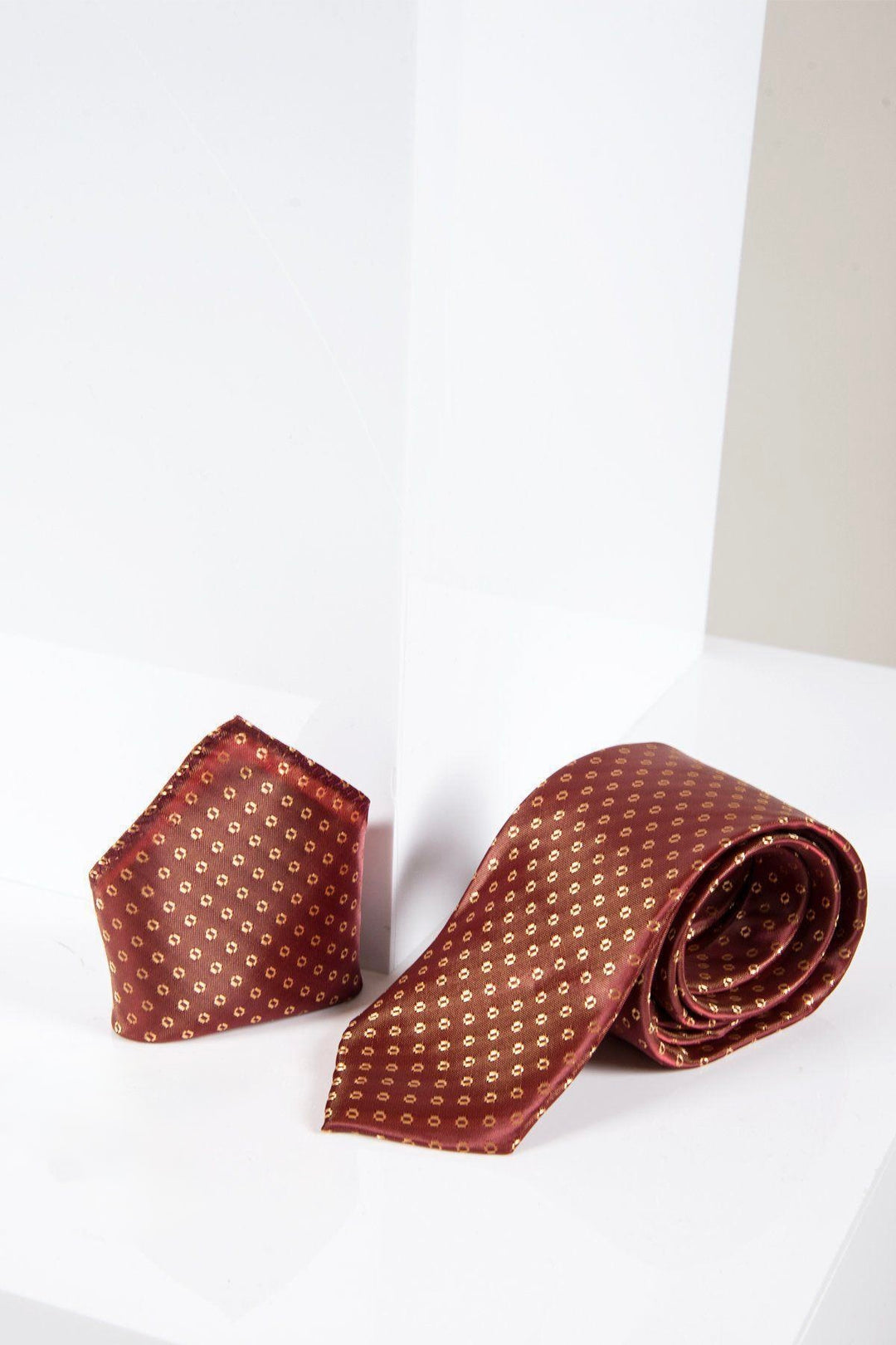 The Marc Darcy TS TUBES set, featuring an orange spot tie and matching pocket square, is displayed on a white geometric surface, offering a refined silk-style texture for an elevated formal look.