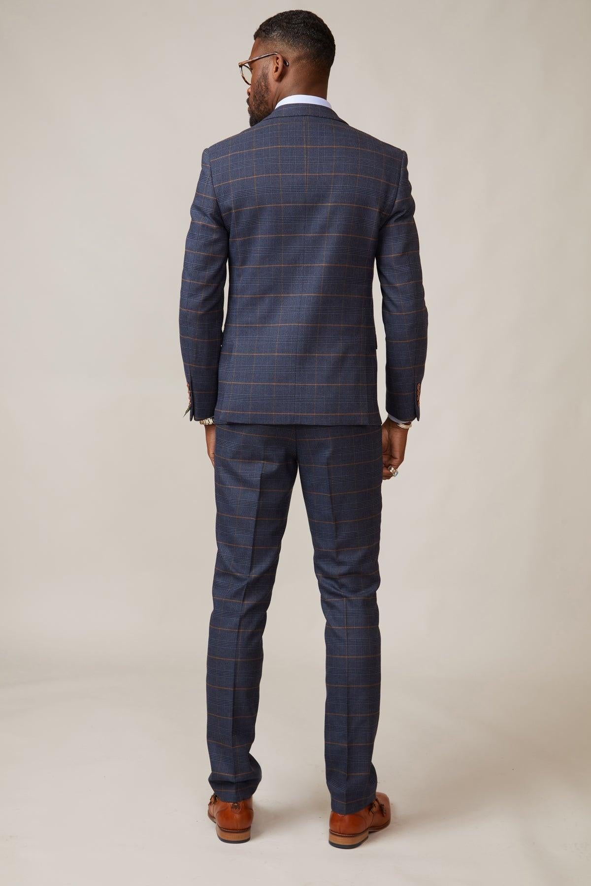 Back view of Boxing Legend Frank Bruno in a marcdarcy Jenson Marine Check suit with rust-colored stripes, white shirt, brown dress shoes, glasses, and rings.