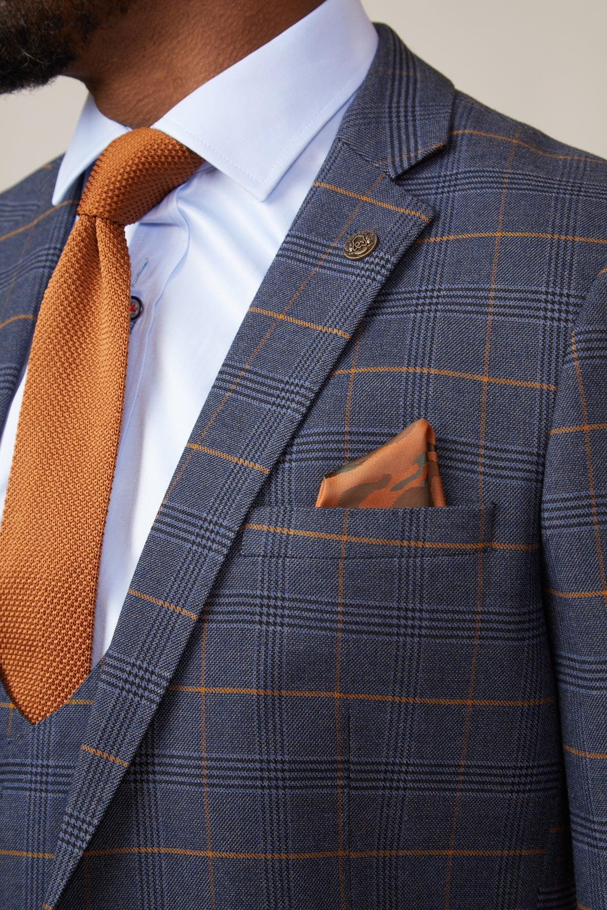 Close-up of Boxing Legend Frank Bruno in a marcdarcy Jenson Marine Check Suit, paired with an orange knit tie, white dress shirt, and patterned pocket square.
