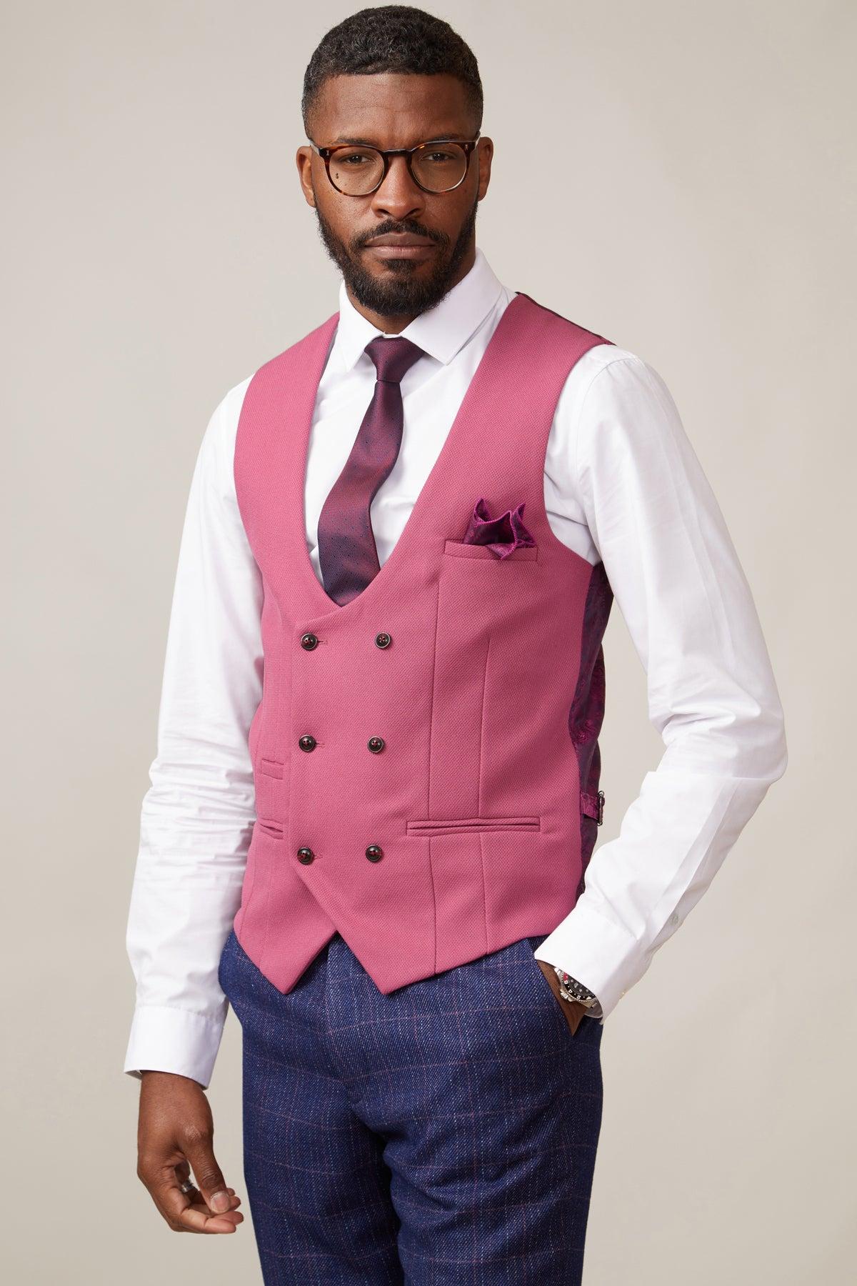 A man in the marcdarcy KELVIN - Berry Double Breasted Waistcoat, paired with a white shirt, dark trousers, and matching pink tie and pocket square, poses against a plain light background.