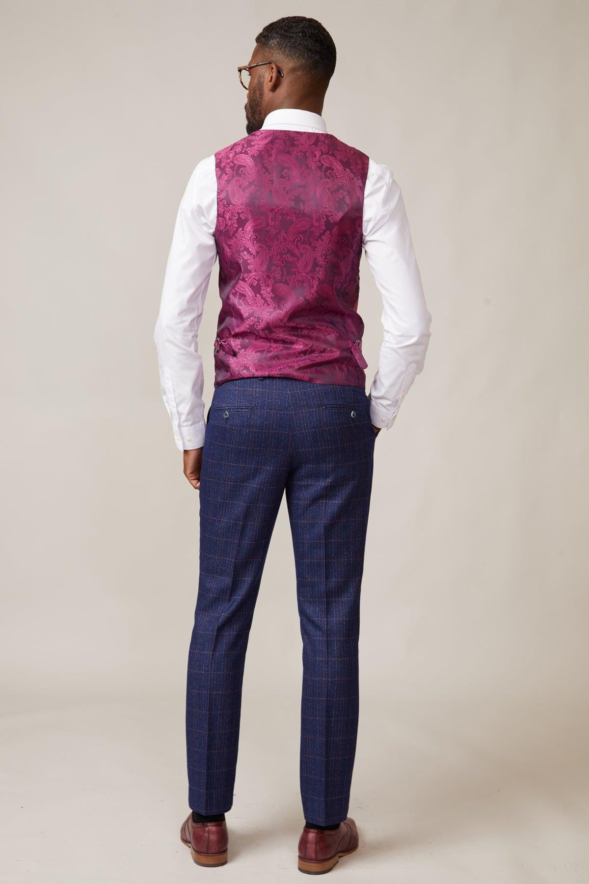 A man stands with his back to the camera, wearing a white shirt, marcdarcys KELVIN - Berry Double Breasted Waistcoat with paisley lining, blue plaid trousers, and brown dress shoes against a plain light background.