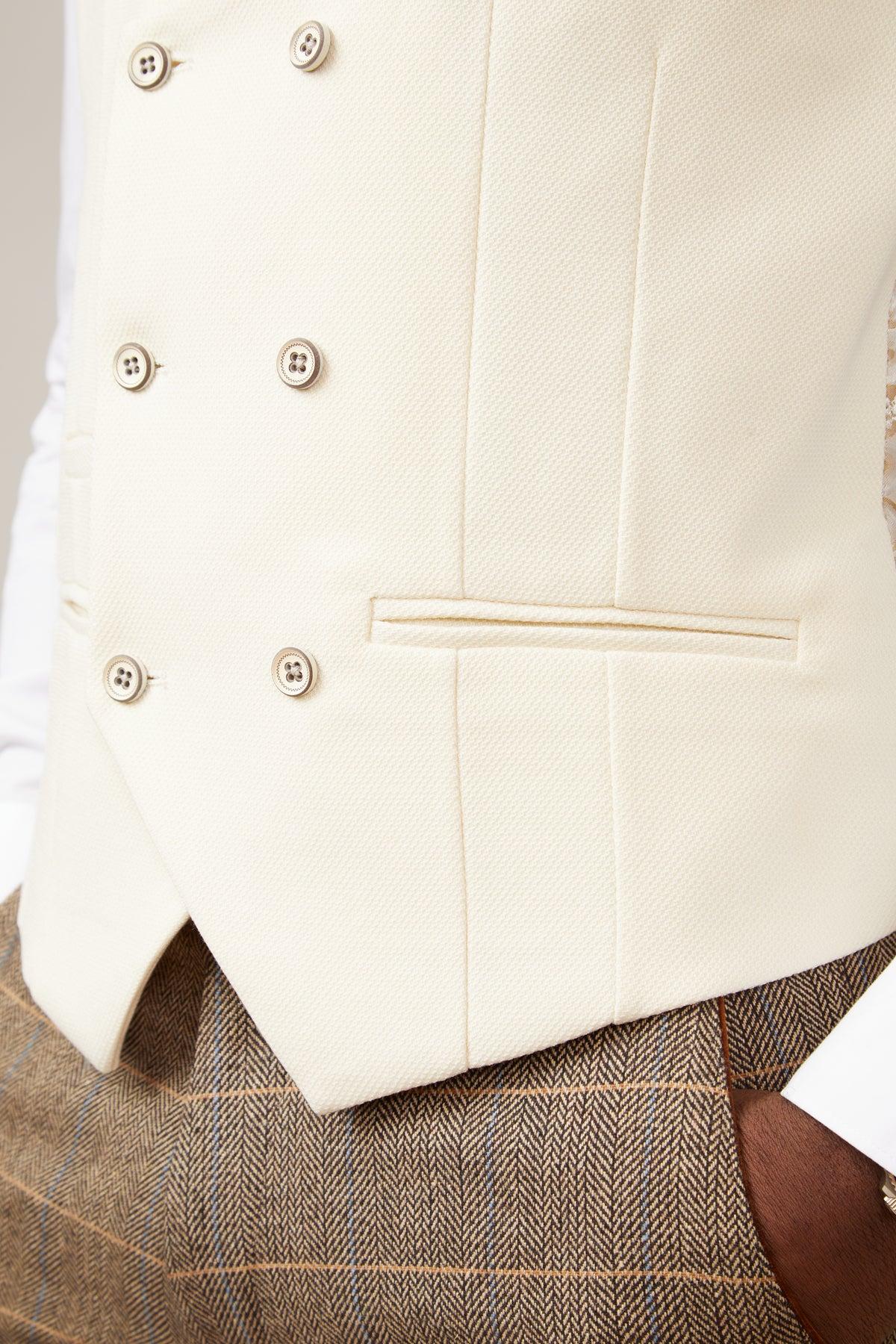 Close-up of the KELVIN Cream Double Breasted Waistcoat by marcdarcy, featuring four buttonholes, a textured weave, British tailoring details like a chest pocket, and styled over a brown herringbone tweed jacket.