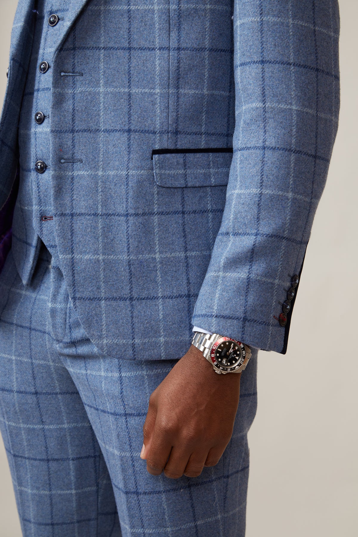A person wearing the marcdarcy CLINTON Blue Tweed Check Blazer and a silver wristwatch stands with one arm relaxed by their side; photo is cropped to show only the lower torso and part of the arm.