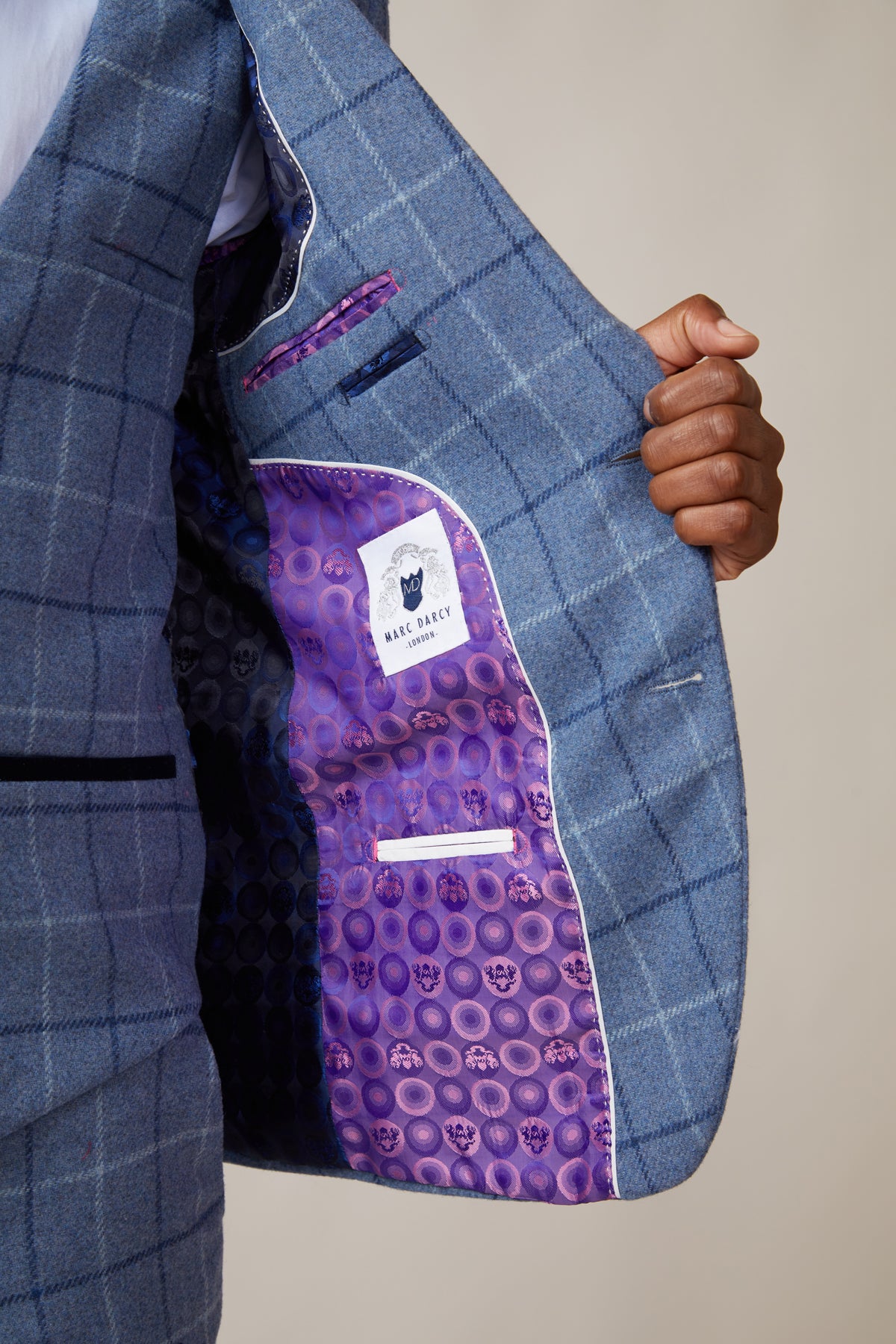 A person holds open their marcdarcy CLINTON - Blue Tweed Check Blazer, revealing a vibrant purple inner lining with circular patterns and a visible marcdarcy label, highlighting the blazer’s heritage style.